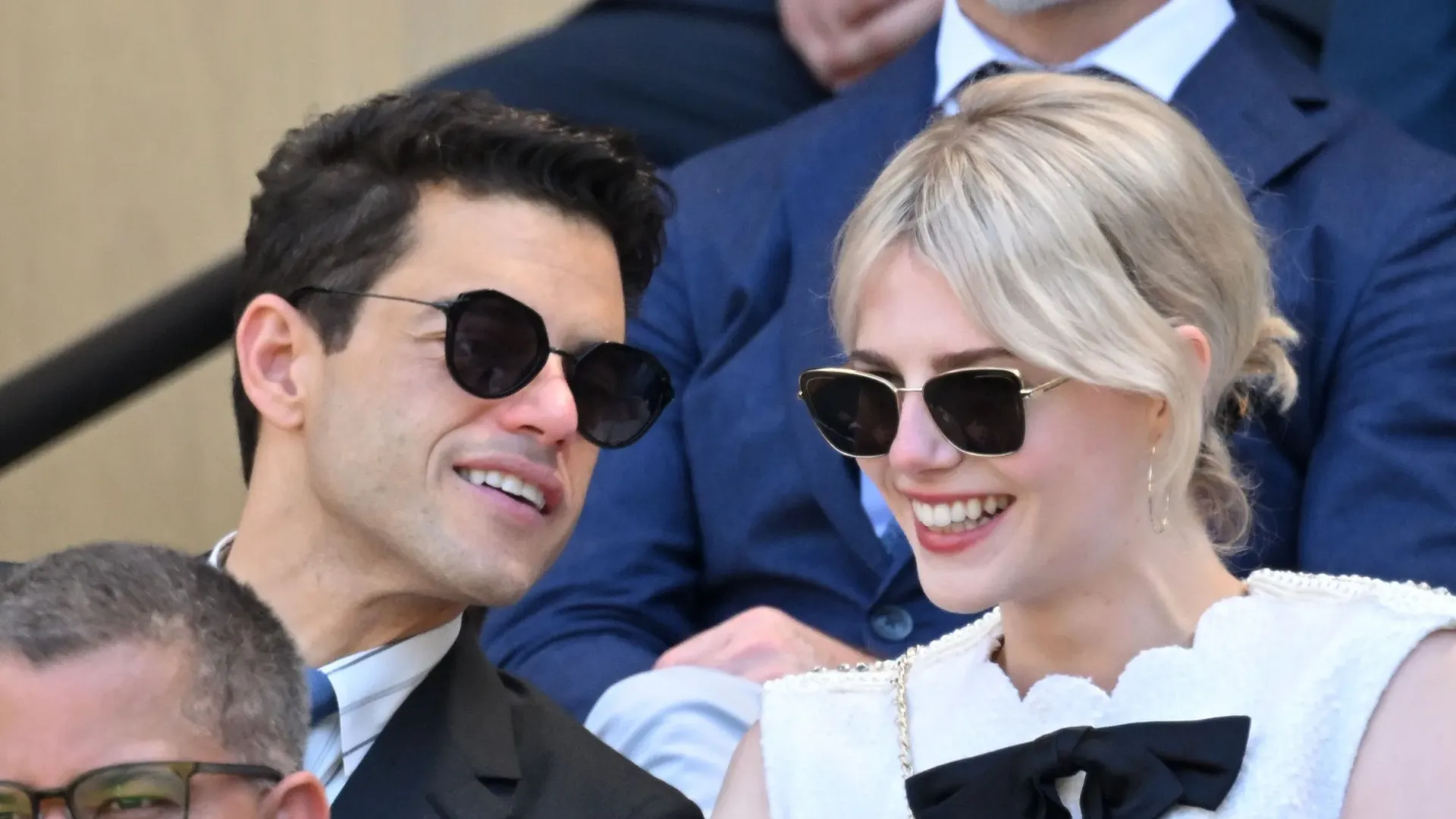 Un uomo e una donna con gli occhiali da sole seduti sugli spalti dello stadio