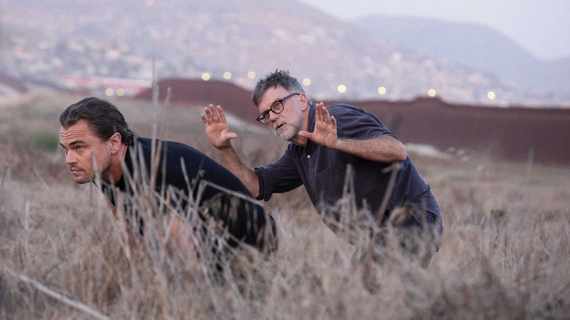 Paul Thomas Anderson e Leonardo DiCaprio camminano accovacciati attraverso l'erba alta