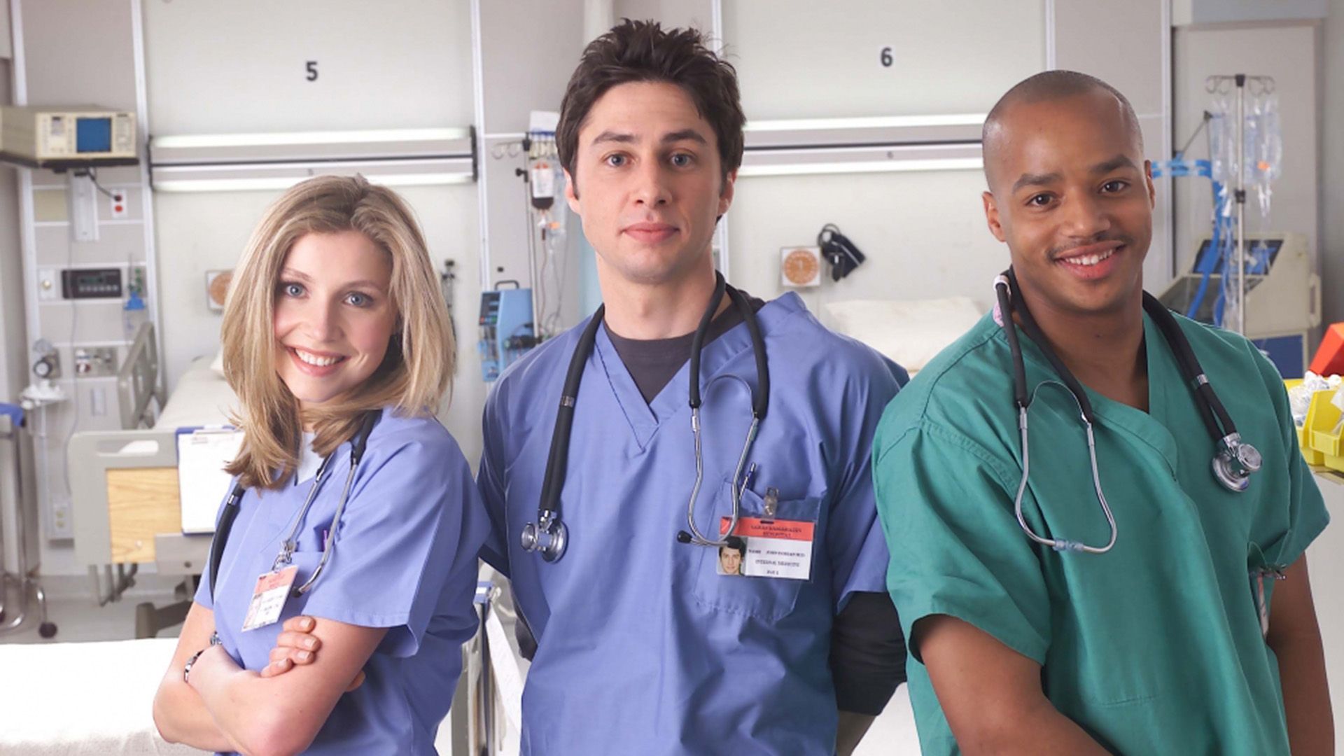 Sarah Chalke, Zach Braff e Donald Faison in camice ospedaliero in piedi in una stanza d'ospedale sorridenti