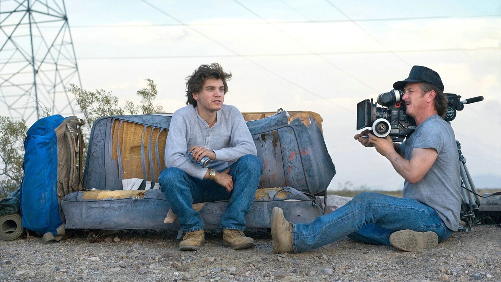 Sean Penn seduto per terra mentre riprende con una cinepresa un giovane su un divano malandato