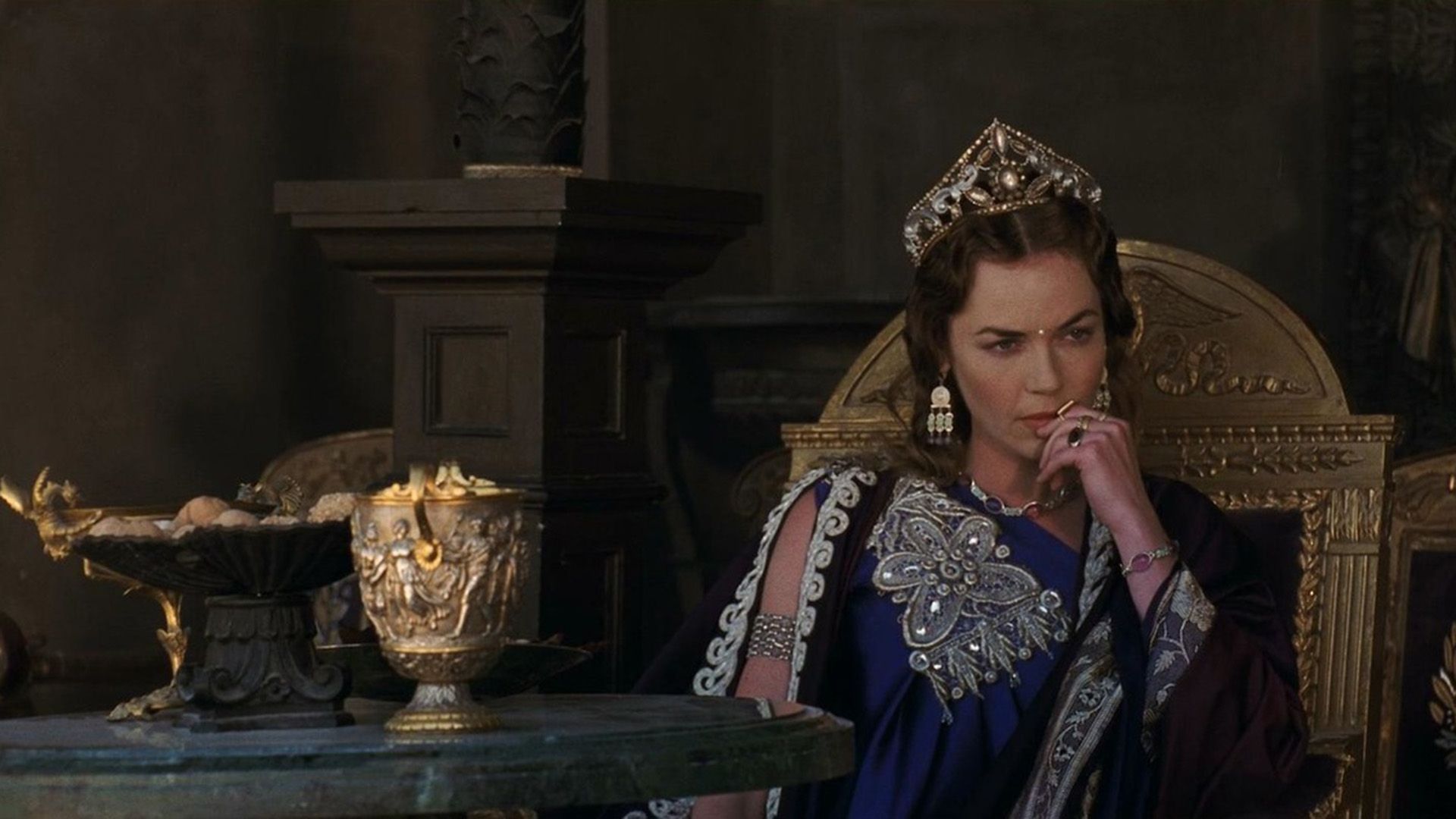 Connie Nielsen nei panni di Lucilla seduta pensierosa su un trono dorato