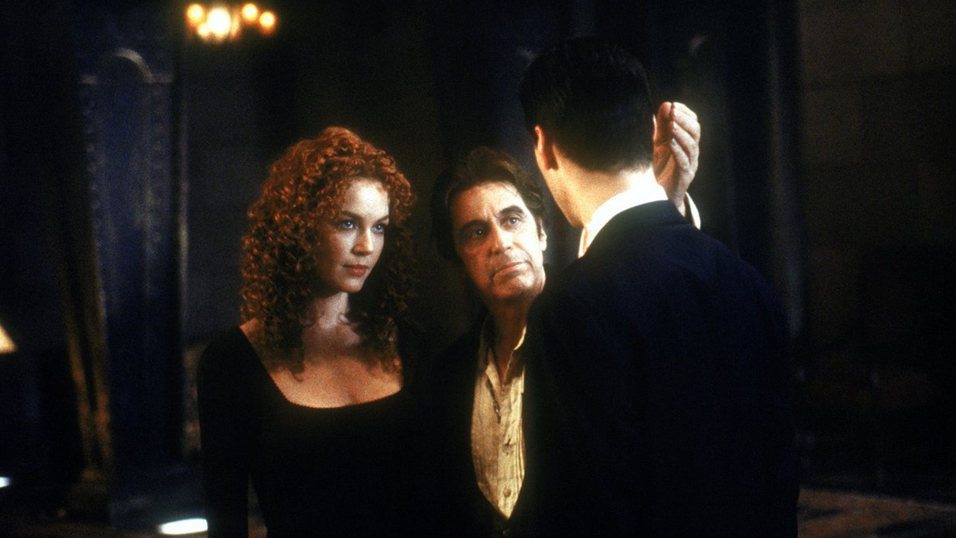 Connie Nielsen con lunghi capelli ricci accanto ad Al Pacino che parla con Keanu Reeves