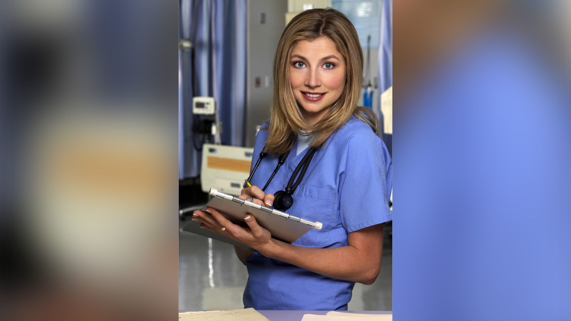 Sarah Chalke in camice da dottore con una cartella clinica in mano