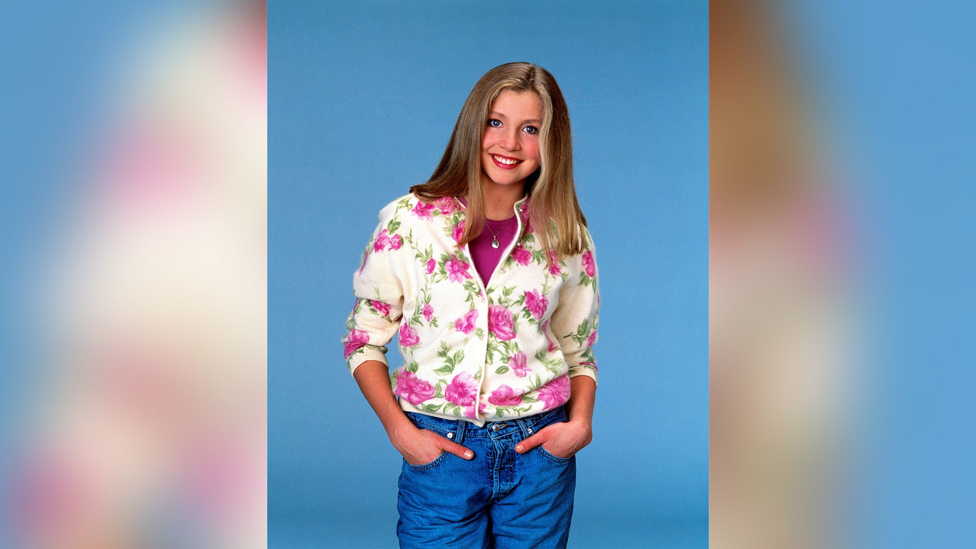 Sarah Chalke in jeans e un maglione bianco con grandi fiori rosa