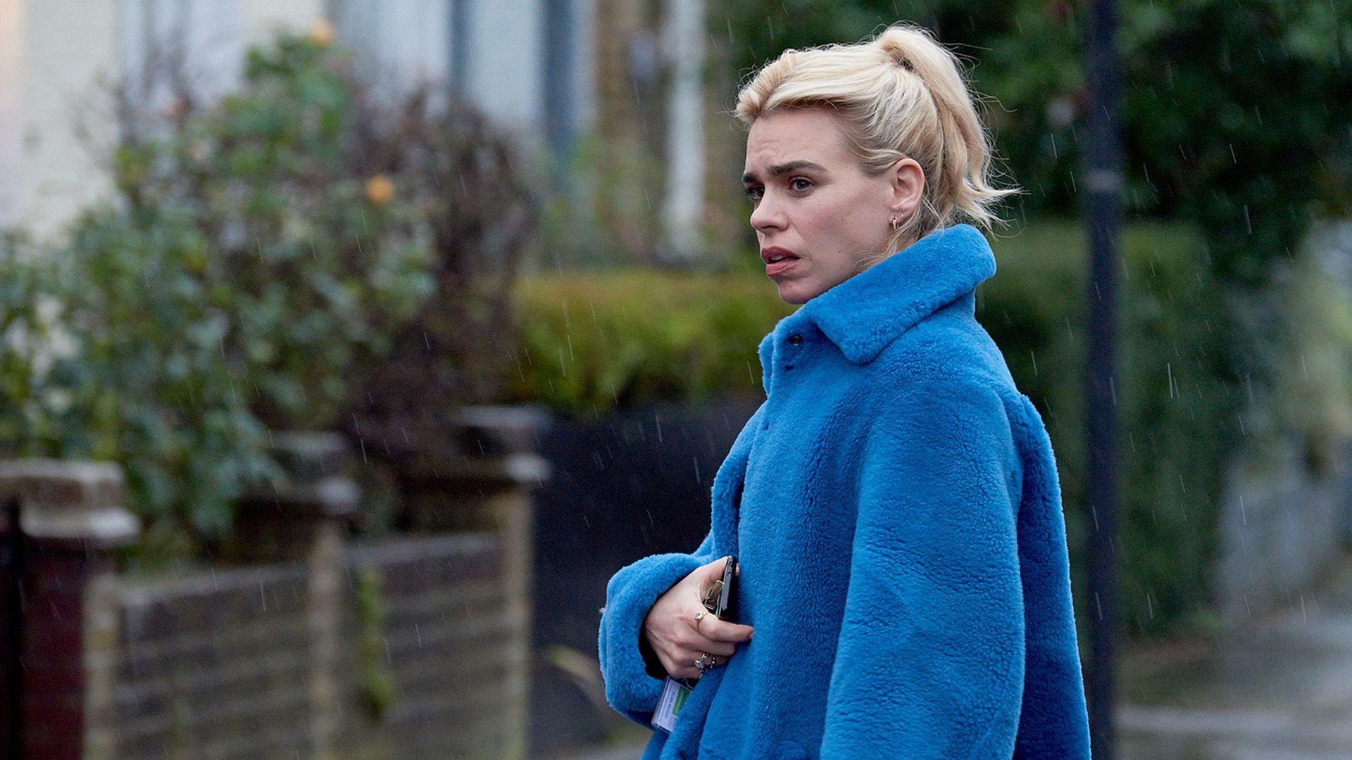 Billie Piper in un cappotto di peluche blu in piedi per strada