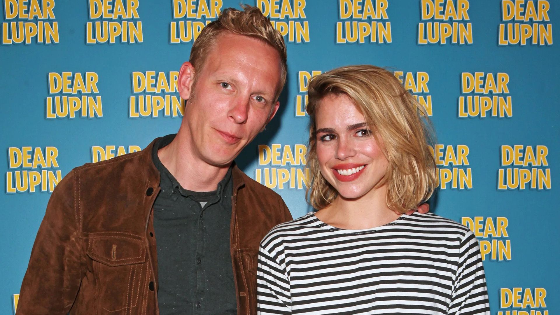 Billie Piper con un maglione a righe e Laurence Fox con una giacca marrone su sfondo blu