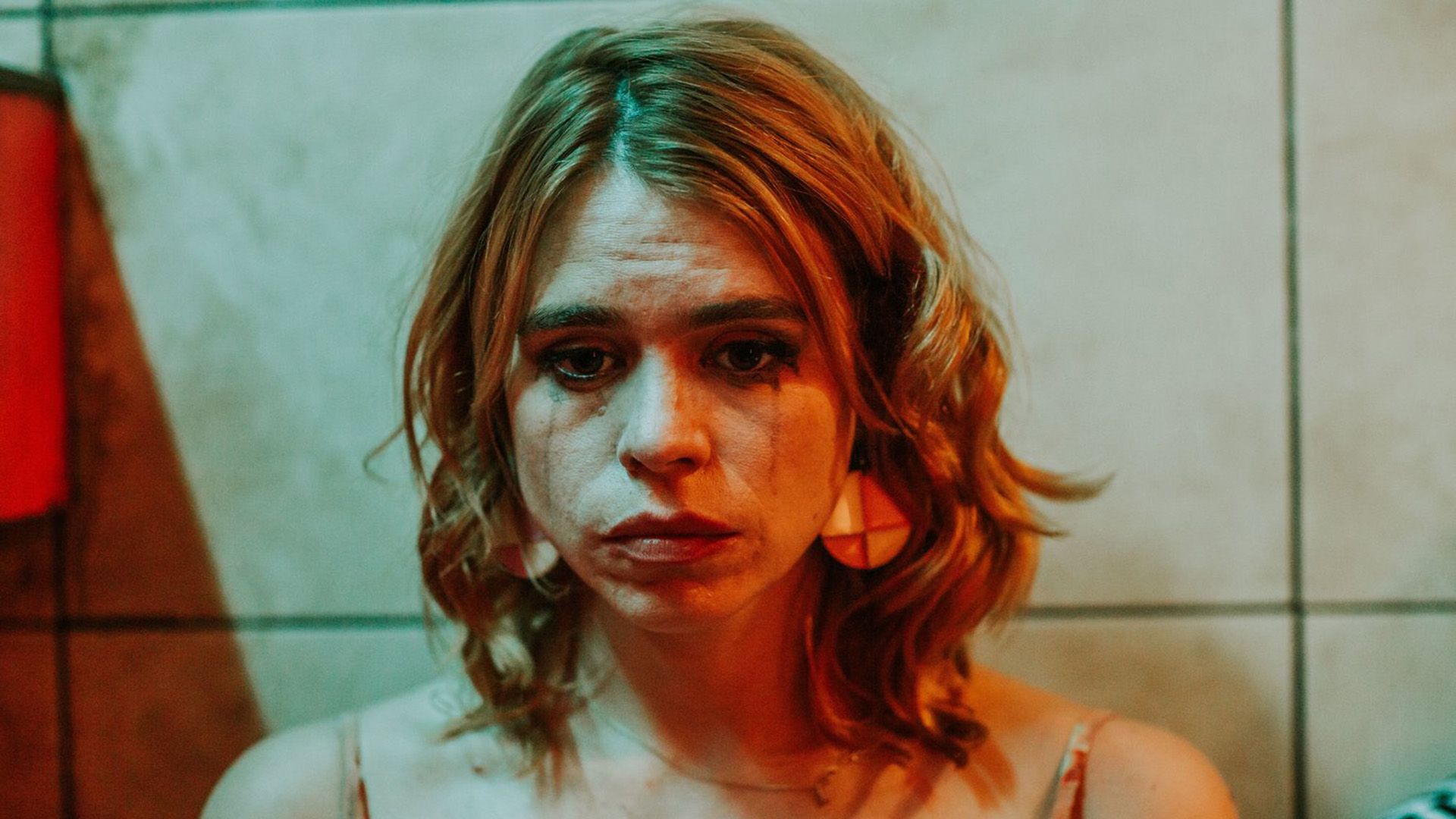 Una Billie Piper triste con il mascara sbavato illuminata da una luce rossa