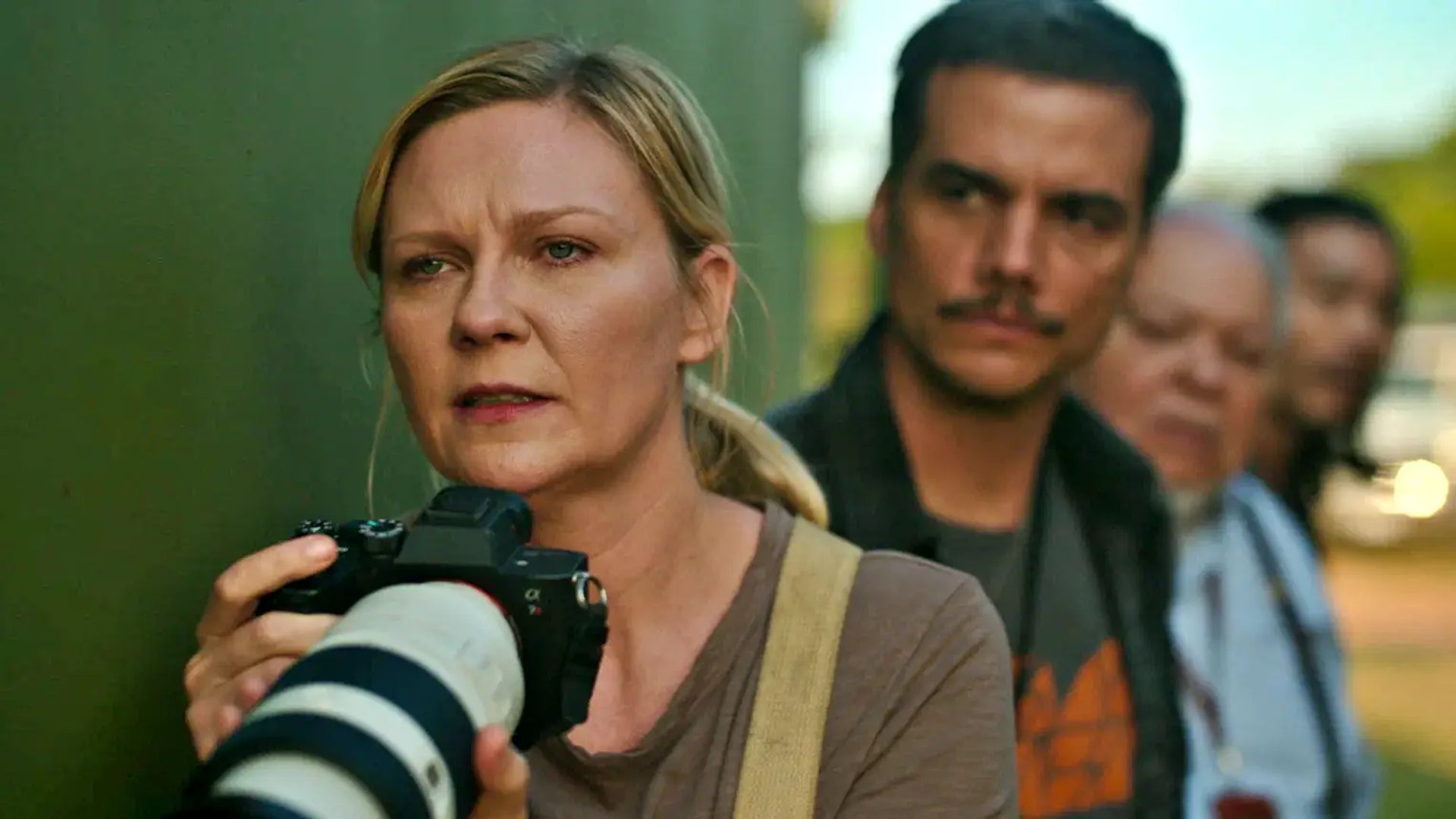 Kirsten Dunst tiene una macchina fotografica e guarda avanti con tensione