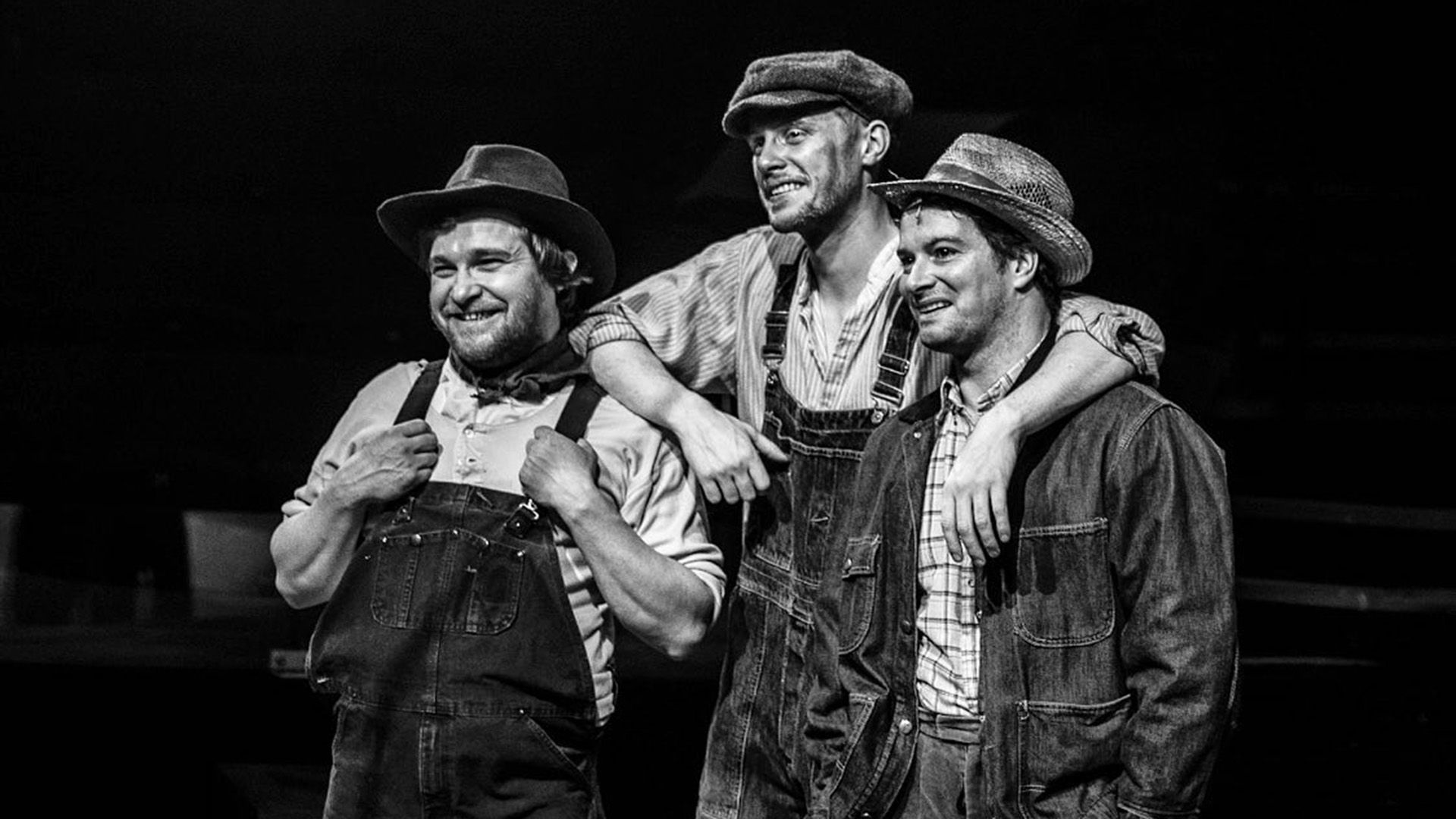 Max Parker e due uomini in salopette di jeans e cappelli da contadino