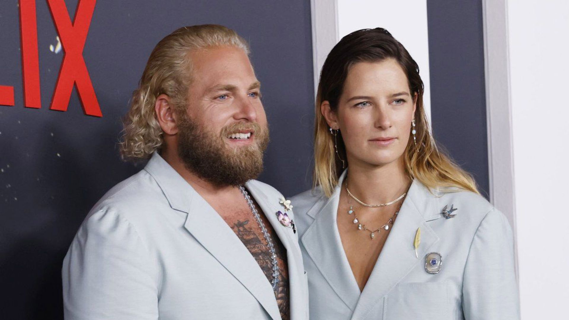 Jonah Hill e Sarah Brady posano davanti a uno sfondo Netflix