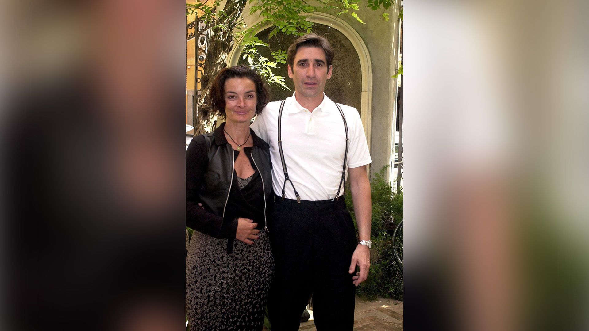 Mary McGuckian in un abito nero e John Lynch in una camicia bianca e bretelle