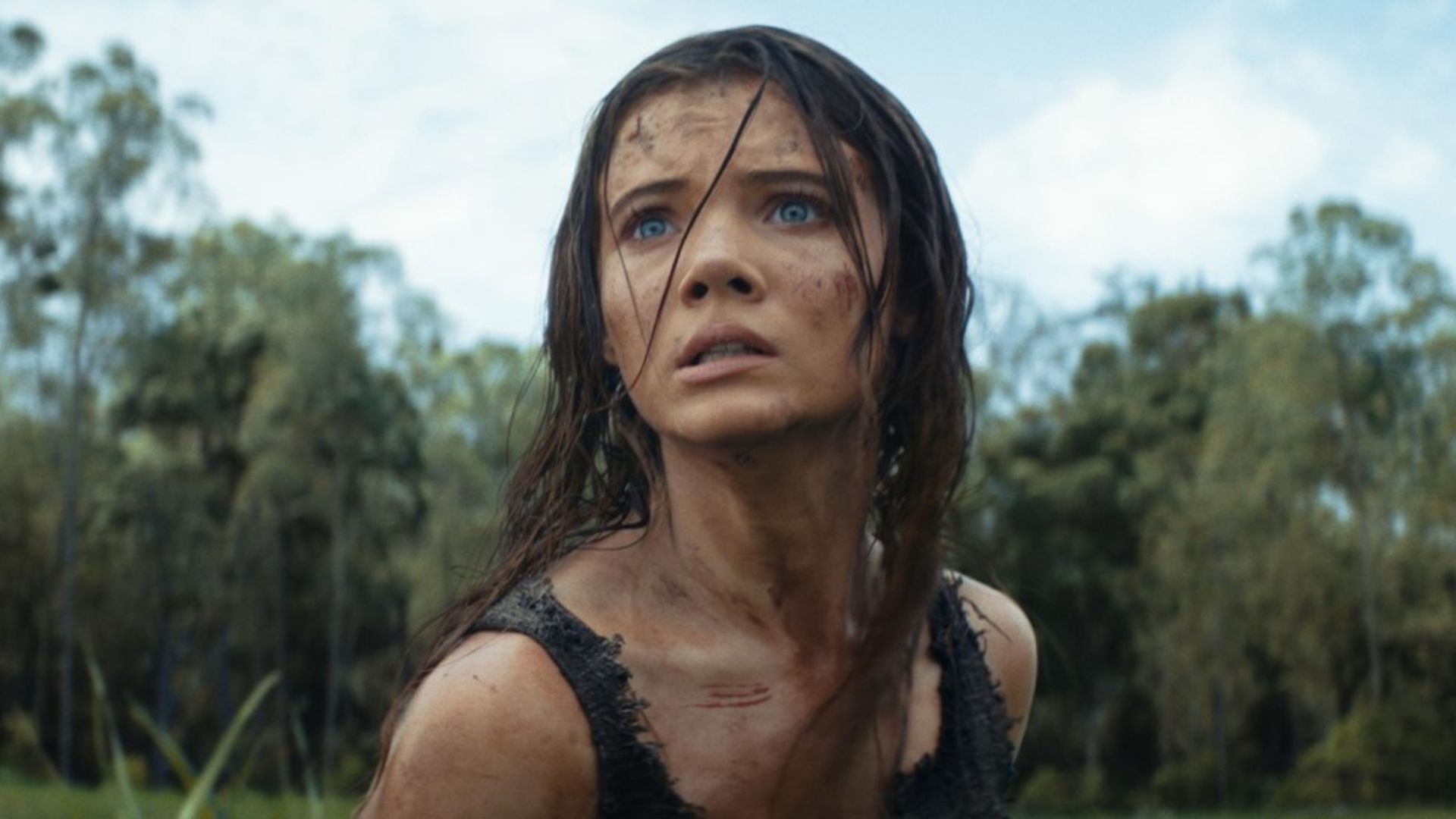 Freya Allan con i capelli arruffati e il viso sporco di terra guarda ansiosamente in lontananza