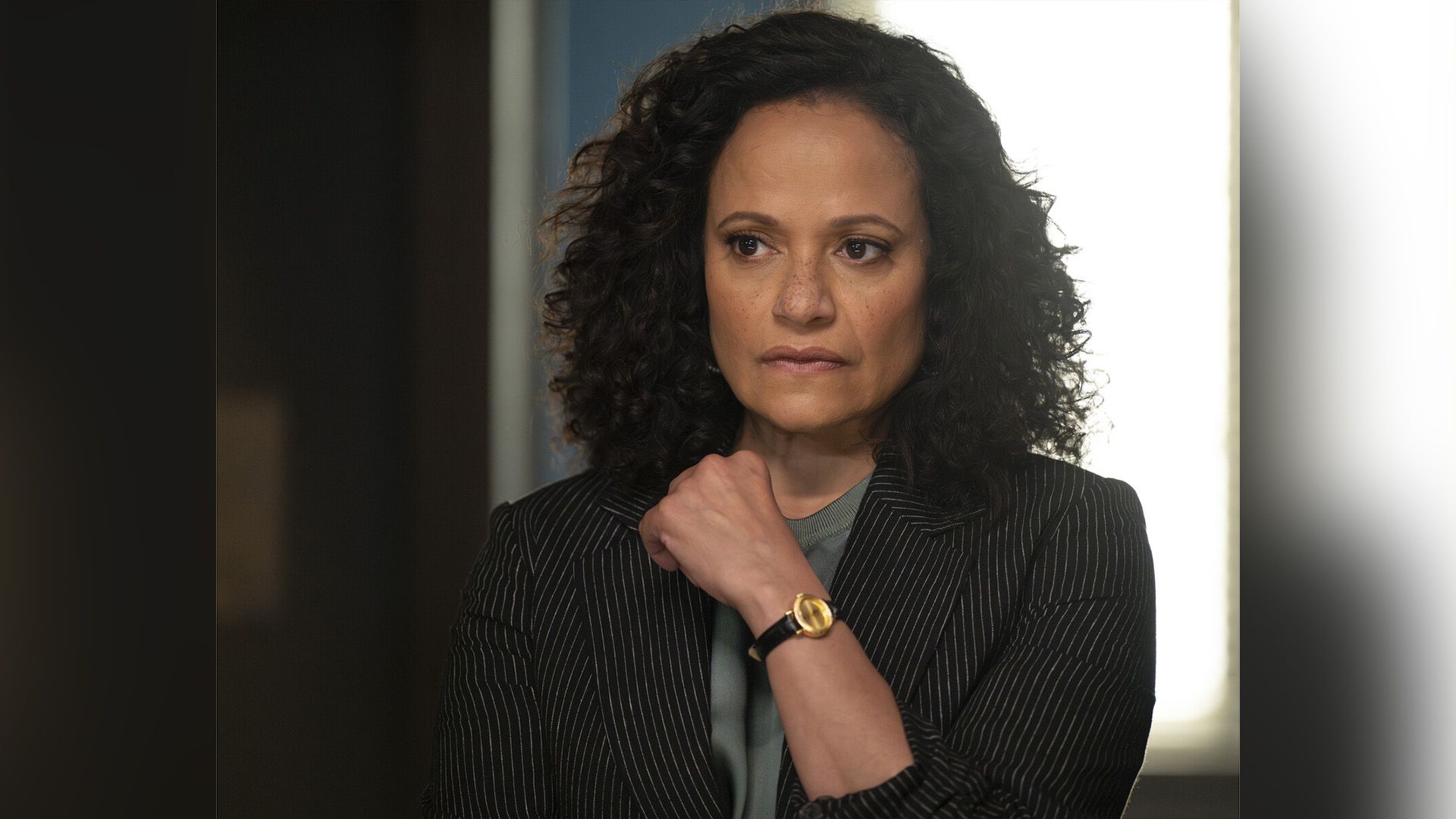 Judy Reyes in blazer a righe guarda pensierosa di lato