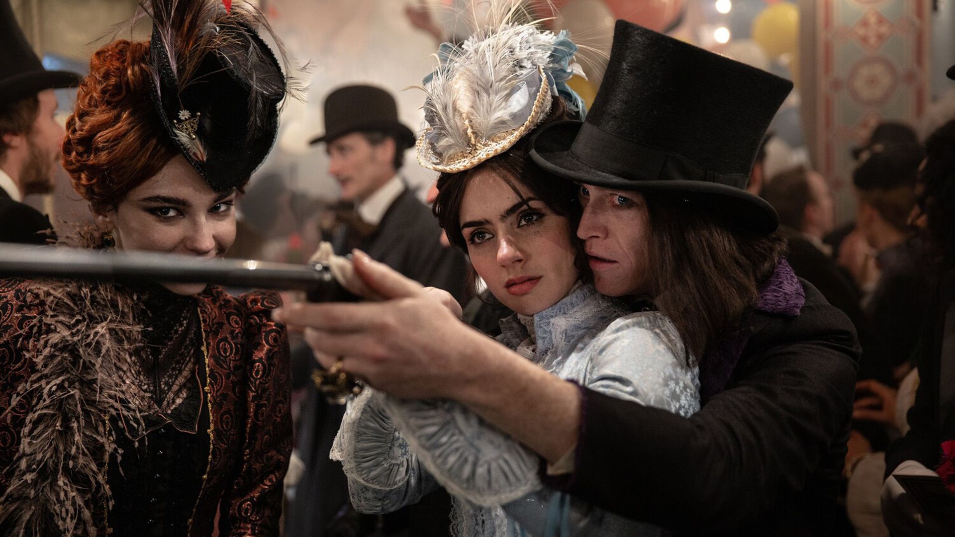 Zoe Bleu in abiti vittoriani punta un fucile aiutata da Caleb Landry Jones con un cilindro