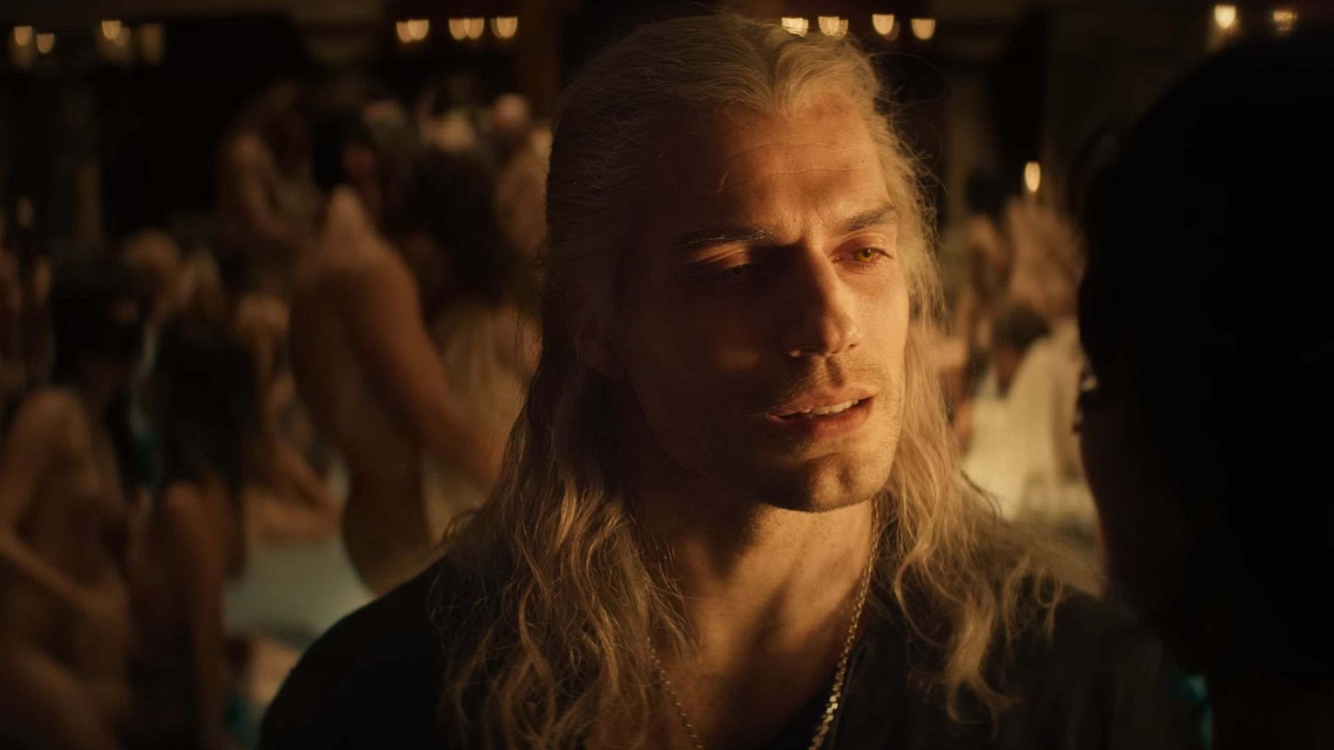 L'attore Henry Cavill con lunghi capelli bianchi che indossa abiti neri