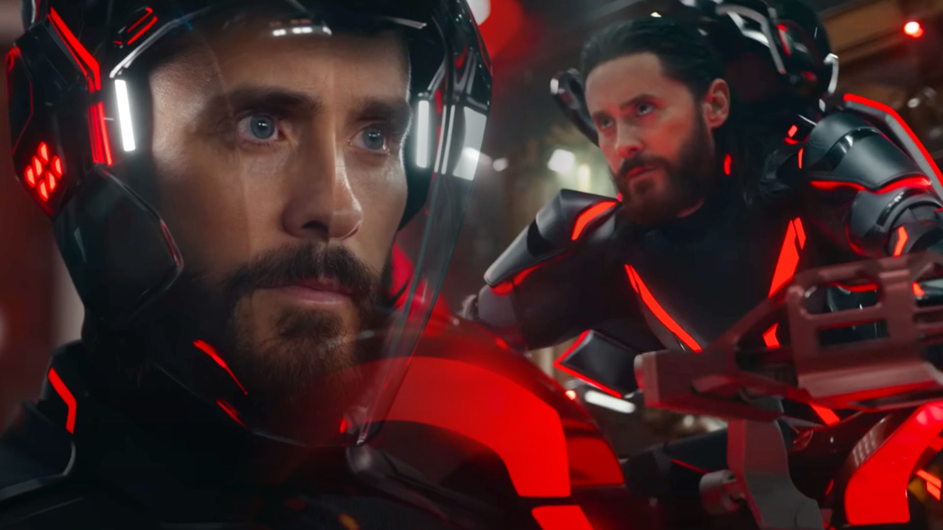 L'attore Jared Leto in una tuta futuristica rossa e nera alla guida di una moto
