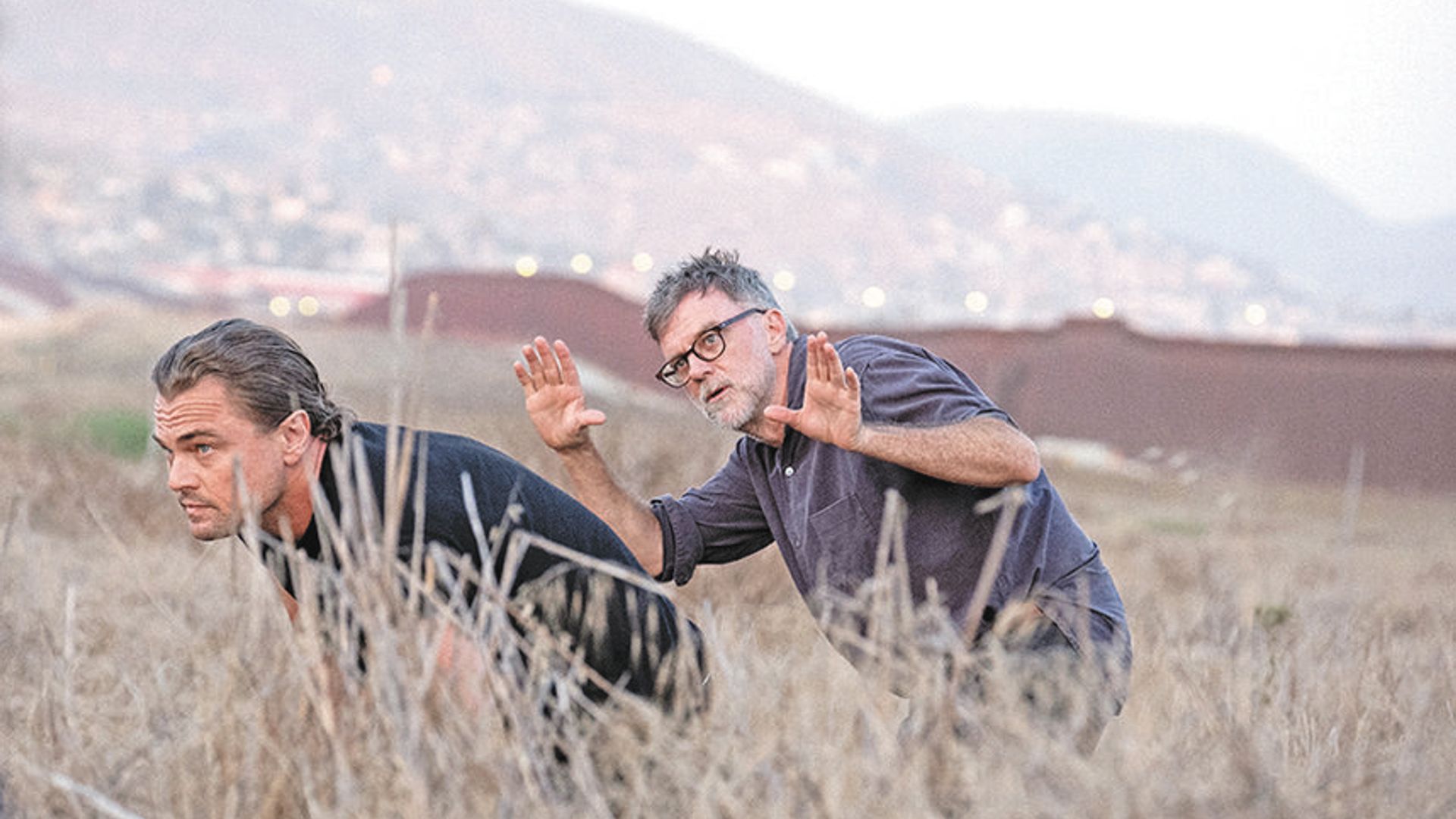 Leonardo DiCaprio e Paul Thomas Anderson camminano attraverso un campo, nascondendosi nell'erba