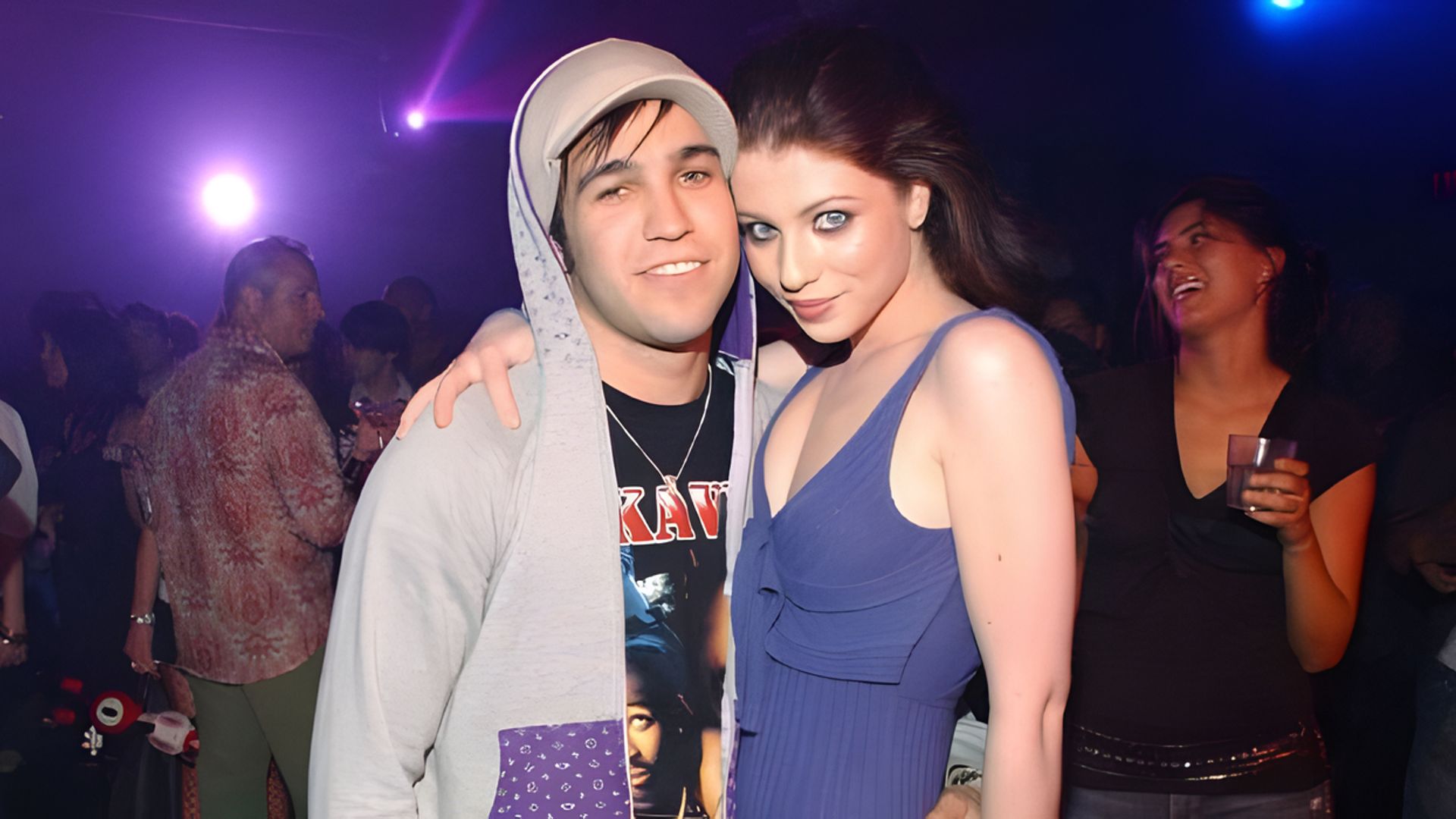 L'attrice Michelle Trachtenberg e il musicista Pete Wentz si abbracciano mentre le persone si divertono sullo sfondo