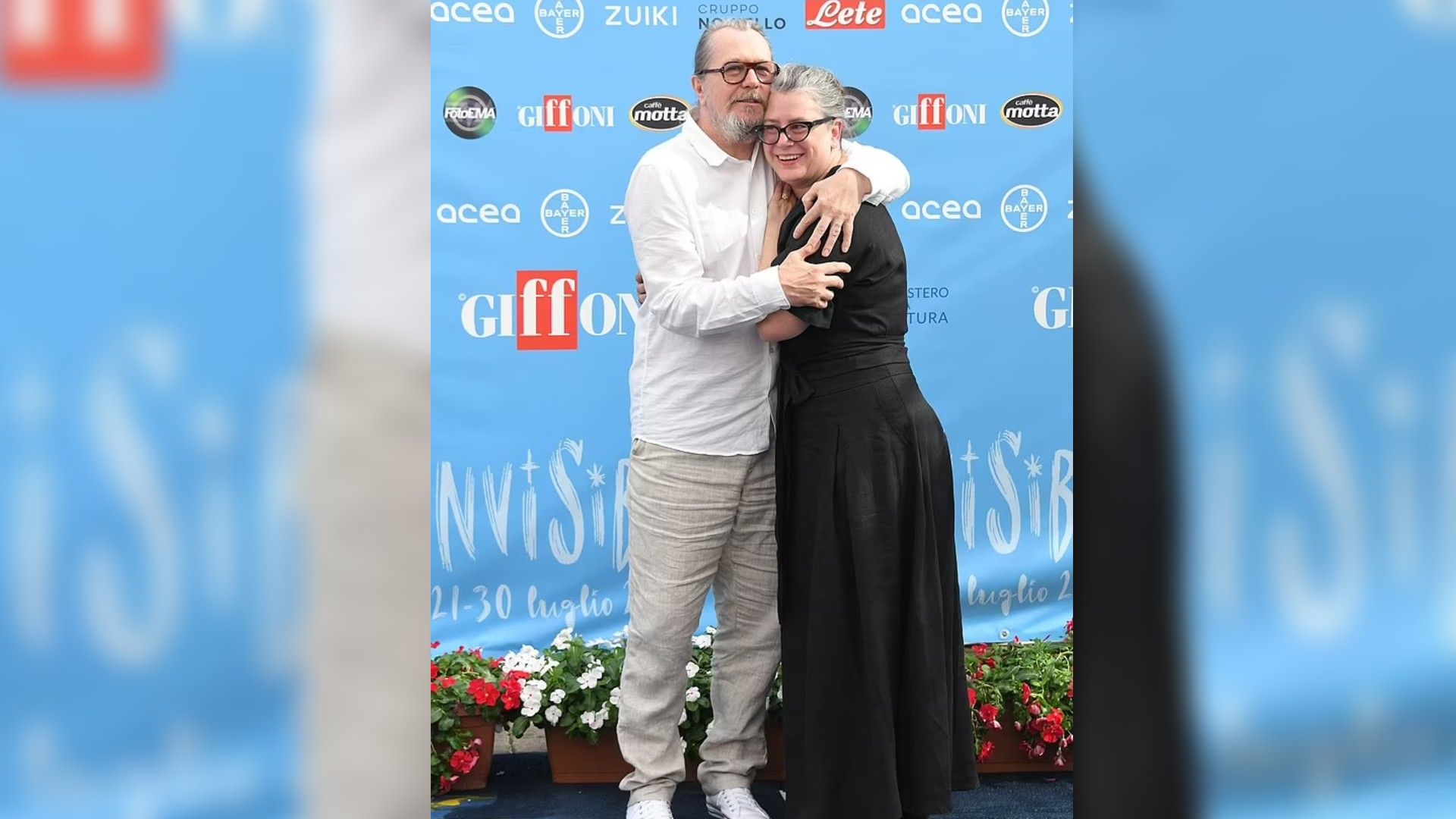 Gary Oldman e Gisele Schmidt che si abbracciano e sorridono davanti a uno striscione blu con i loghi di Giffoni