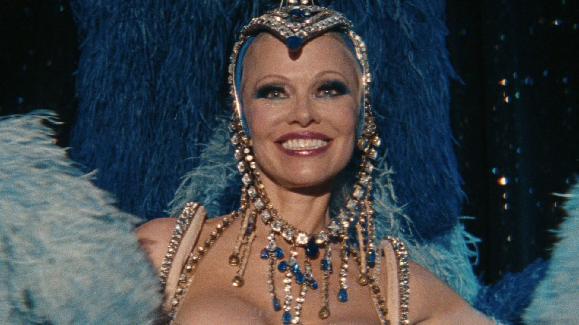 Pamela Anderson in un abito fatto di piume blu e turchesi, perline e strass