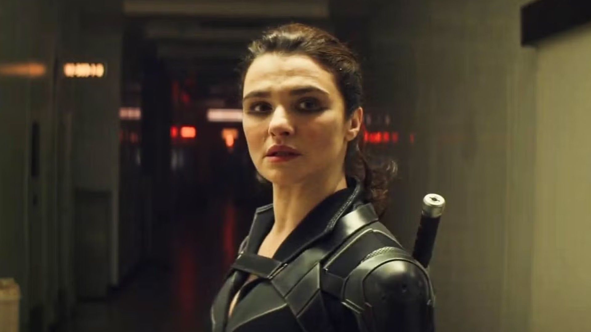 L'attrice Rachel Weisz con i capelli raccolti in una coda di cavallo, indossa un costume da supereroe nero