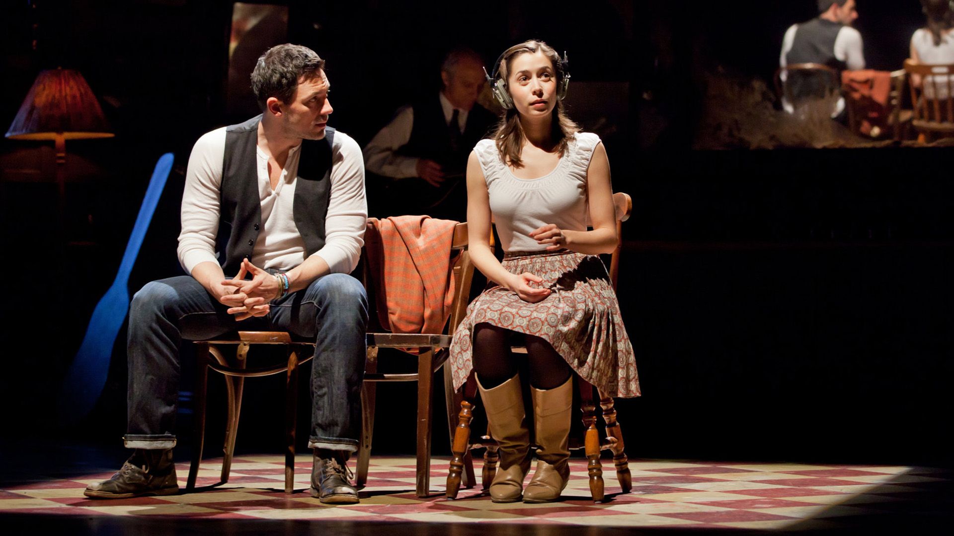 Cristin Milioti e Steve Kazee seduti su sedie sul palco nella produzione 'Once'