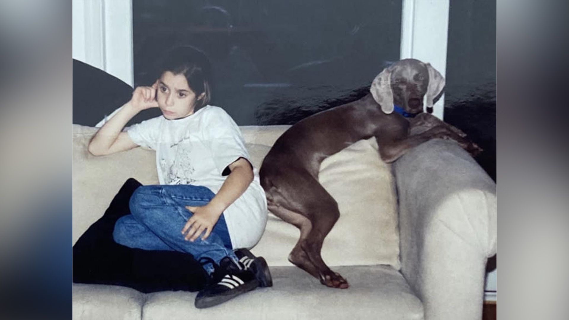 Cristin Milioti seduta su un divano nella sua infanzia, con un grande cane seduto accanto a lei