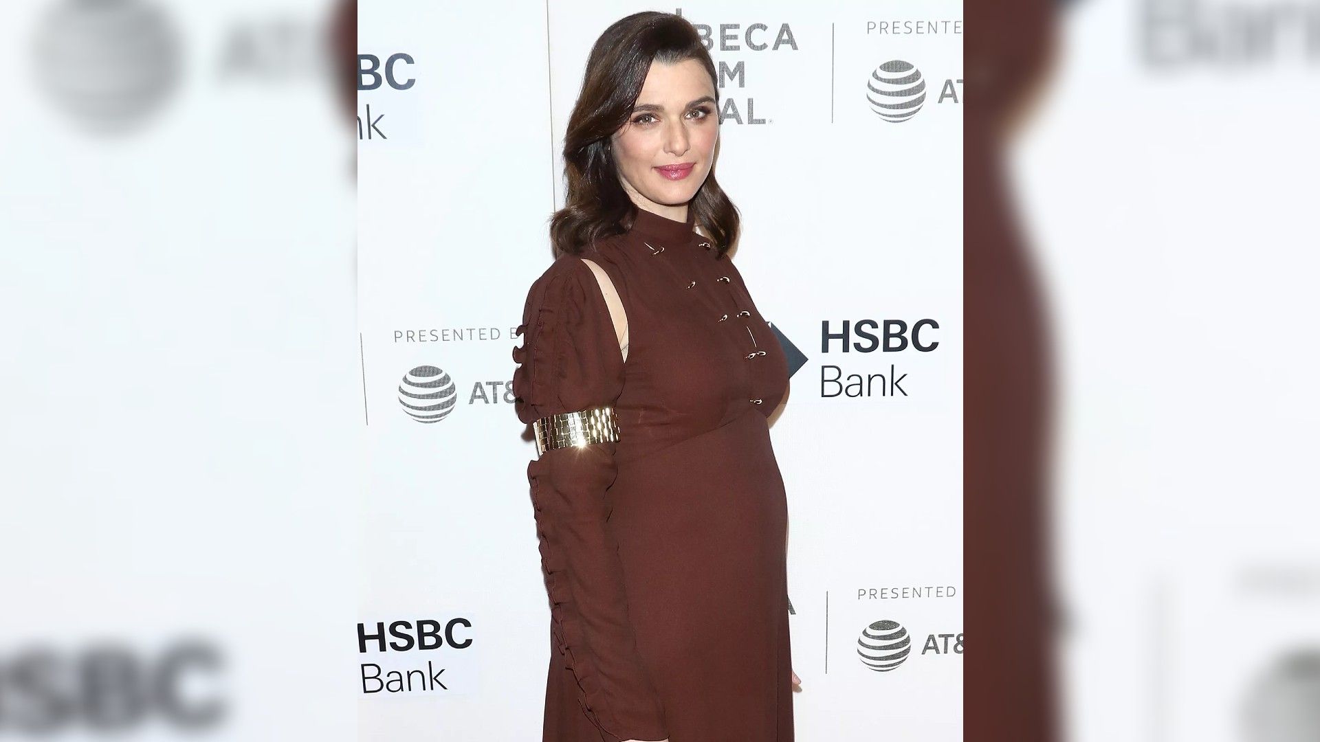 Rachel Weisz in un vestito bordeaux a figura intera, che mostra chiaramente che aspetta un bambino