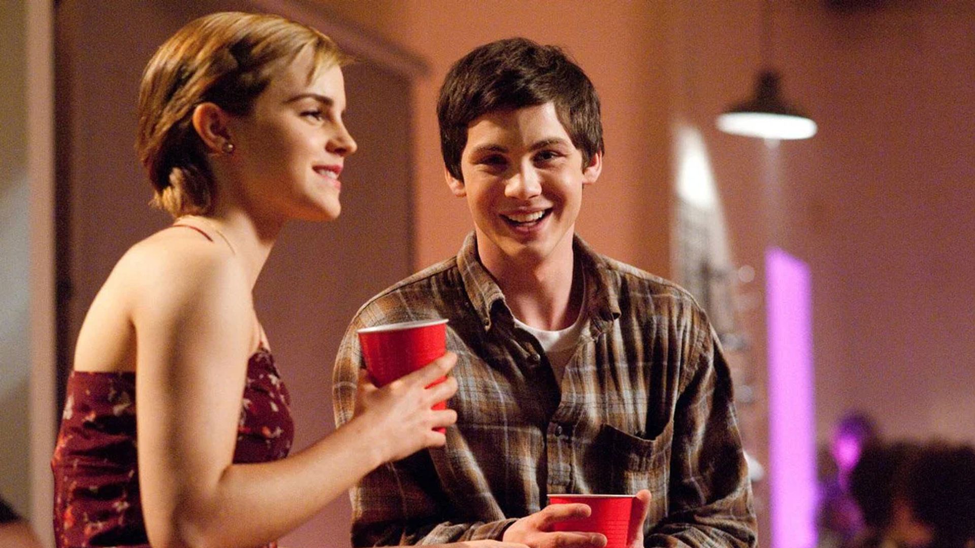 Emma Watson e Logan Lerman seduti al tavolo con bicchieri di plastica in mano