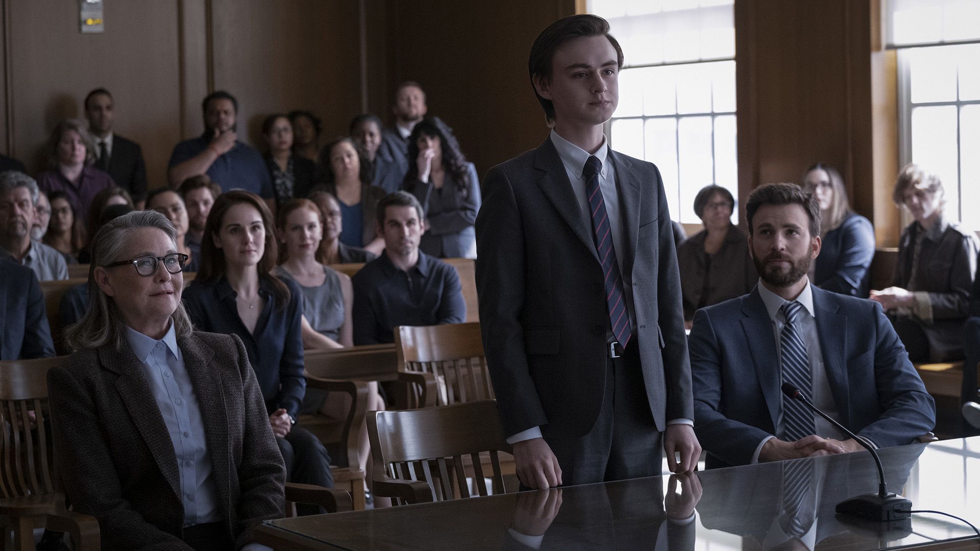 Jaeden Martell si trova al tavolo in aula, seduto accanto a lui c'è Chris Evans, con spettatori sullo sfondo