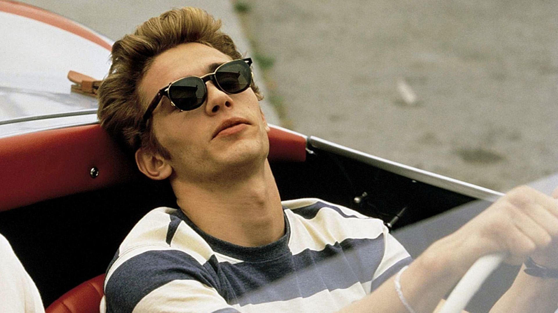 James Franco in una maglietta a righe e occhiali da sole scuri mentre guida una decappottabile