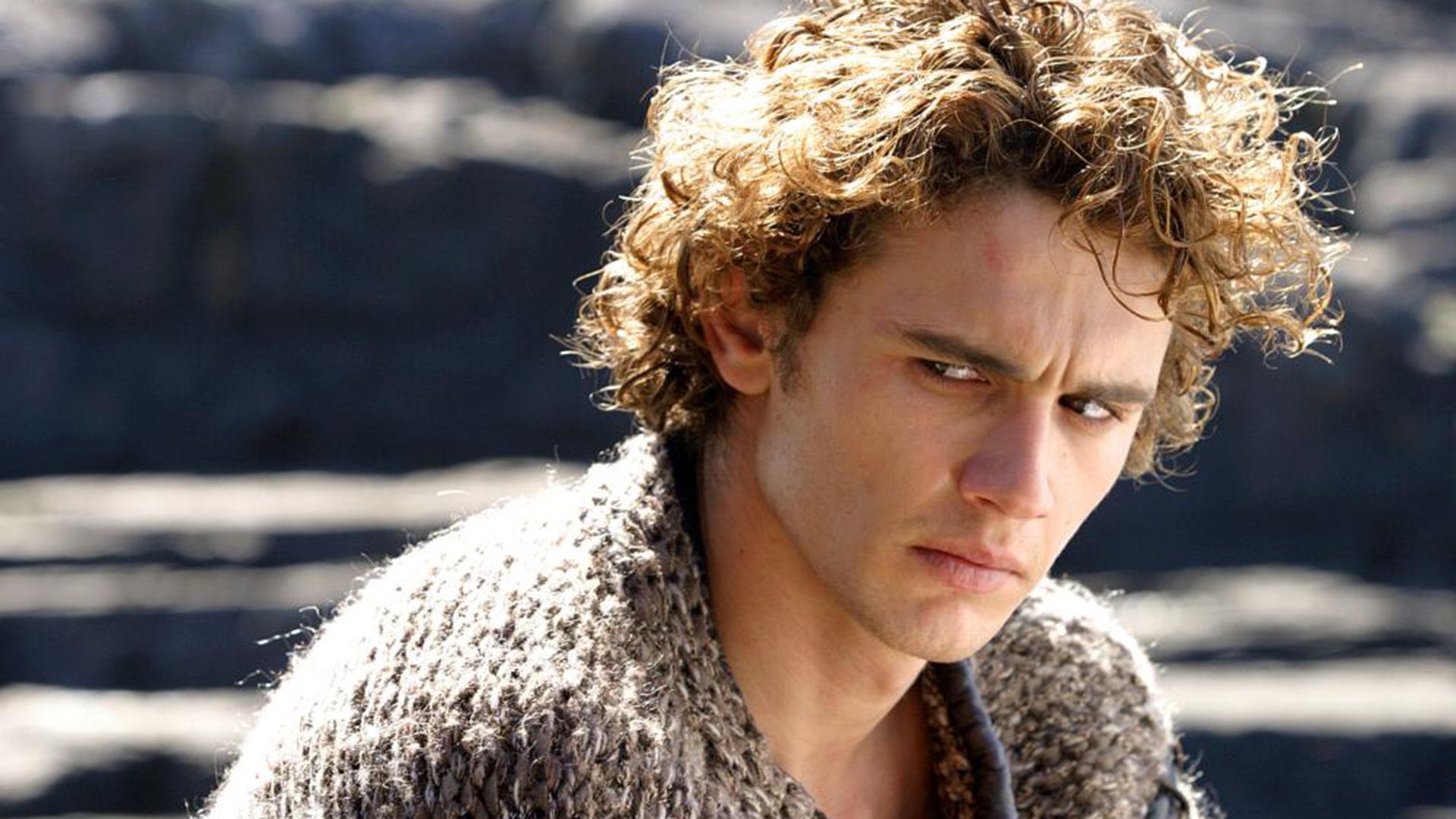 James Franco with golden curls looks gloomily to the side