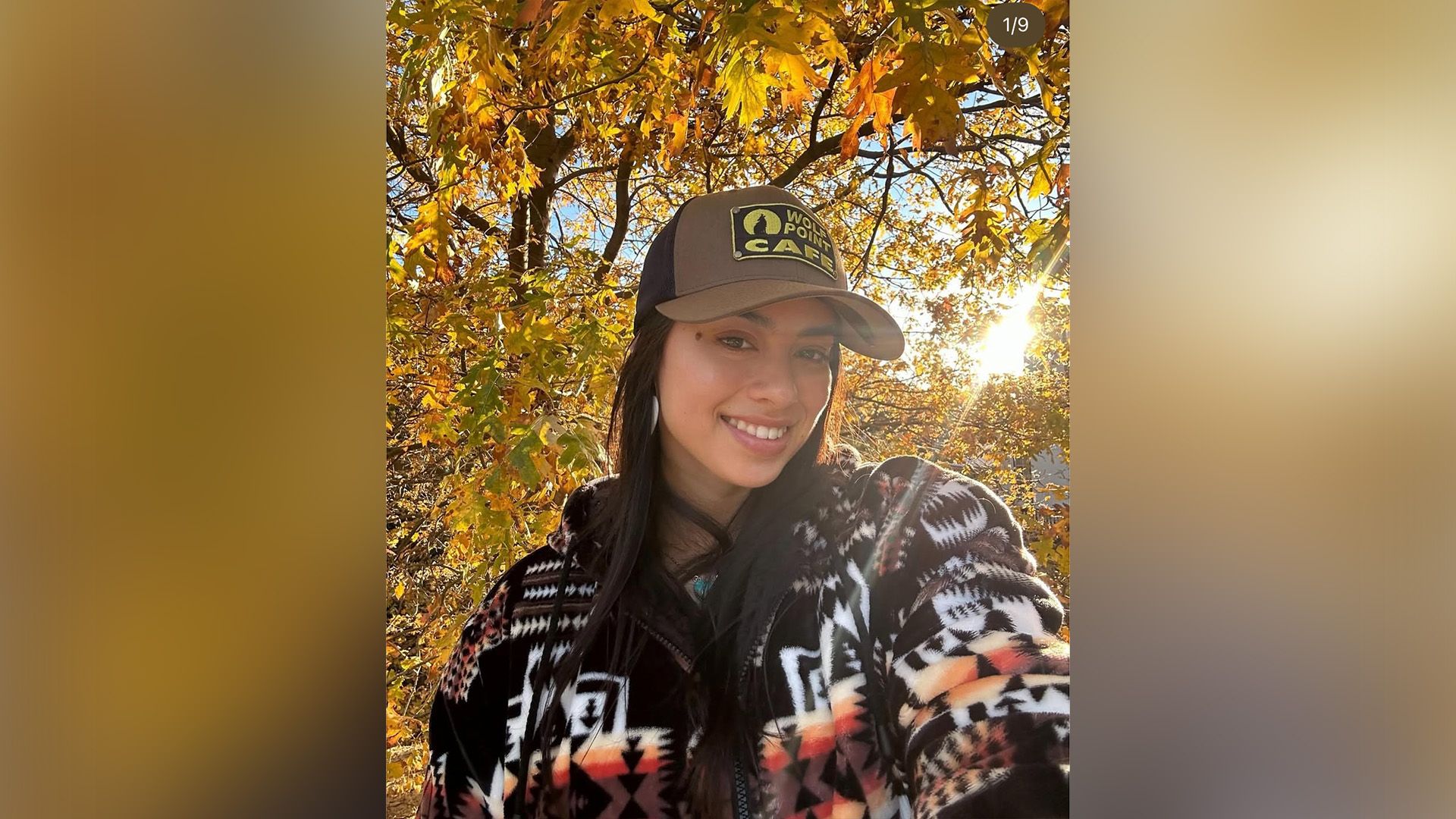 Attrice Amber Midthunder con un berretto da baseball e un maglione caldo su uno sfondo di fogliame autunnale