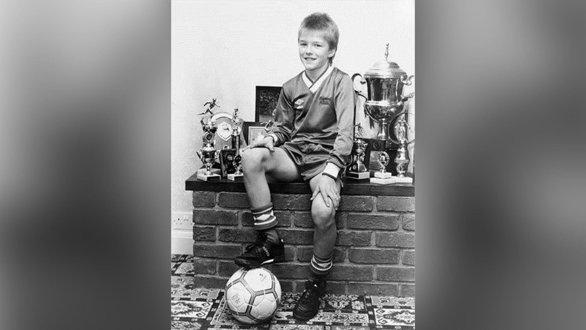 David Beckham da bambino in una divisa da calcio e con un pallone