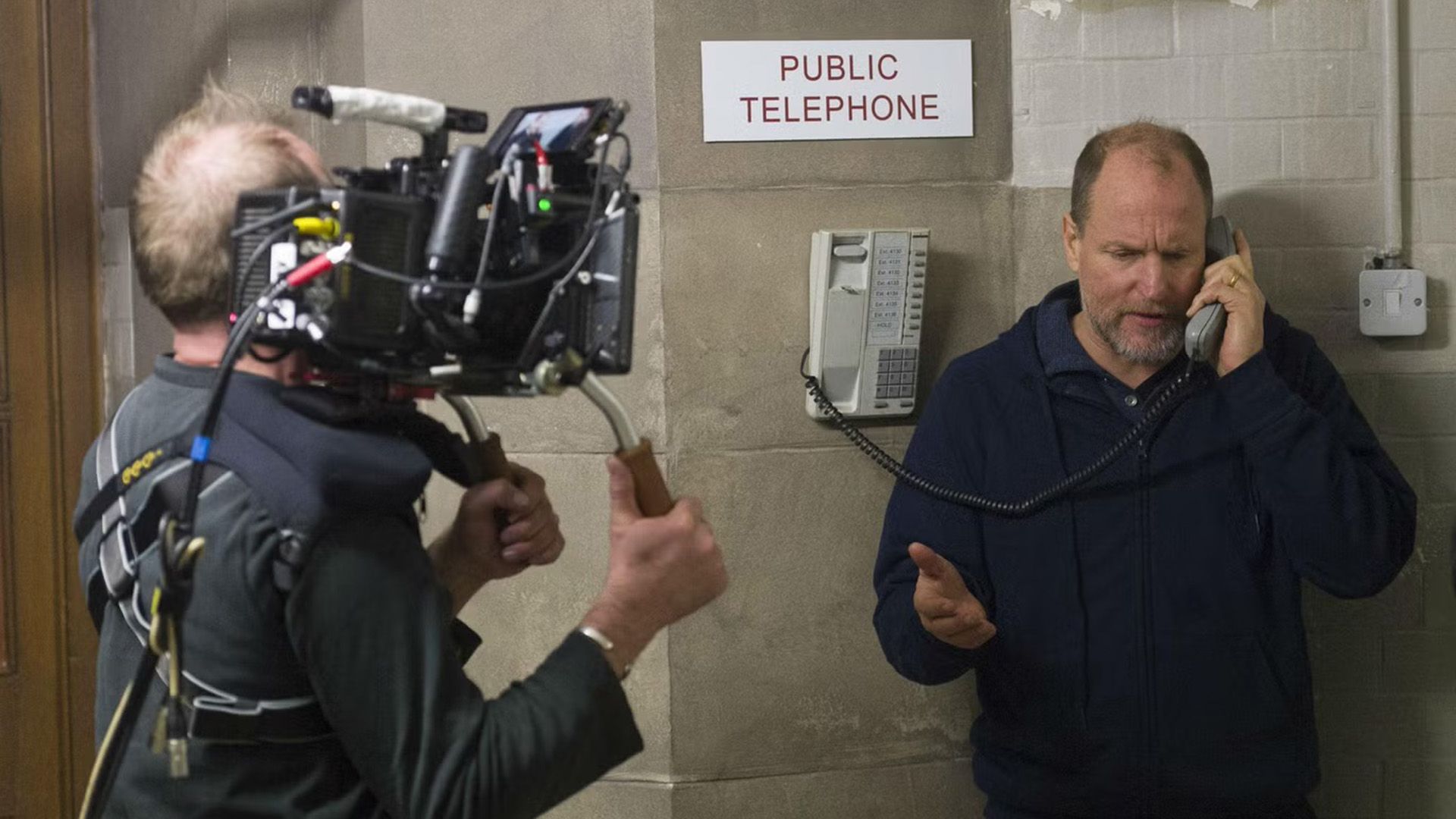 Woody Harrelson parla in un telefono pubblico mentre viene filmato da un cameraman