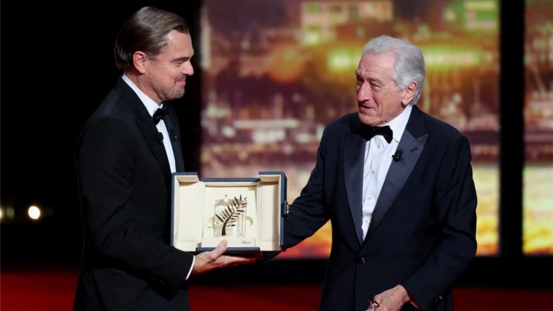 L'attore Leonardo DiCaprio sorride mentre consegna a Robert De Niro la 'Palme d'Or' sul palco