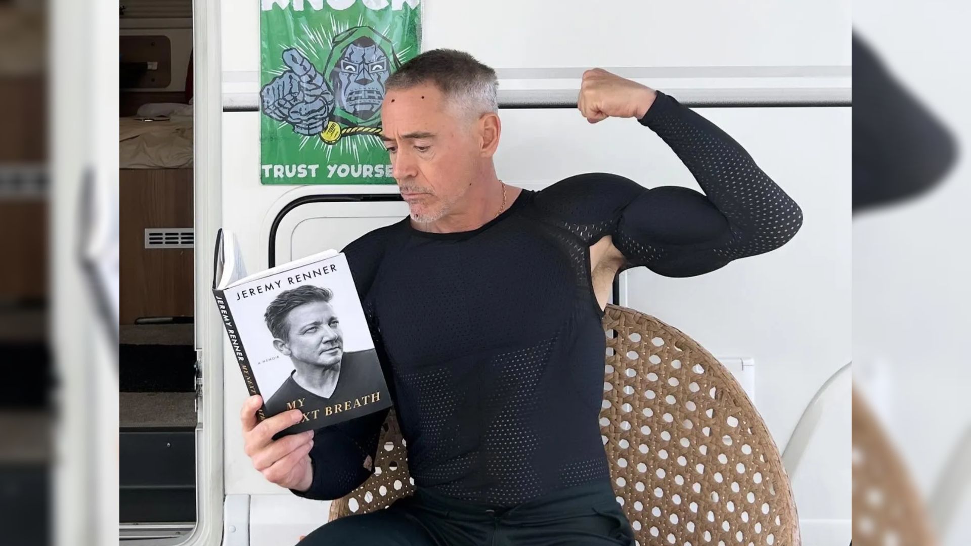 L'attore Robert Downey Jr. in abiti attillati siede vicino a un trailer e tiene un libro in mano