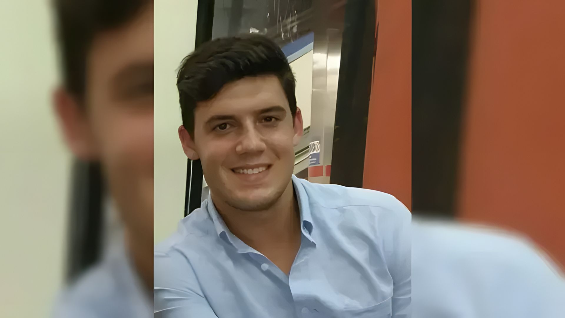 Un giovane sorride alla telecamera, lo sfondo è sfocato
