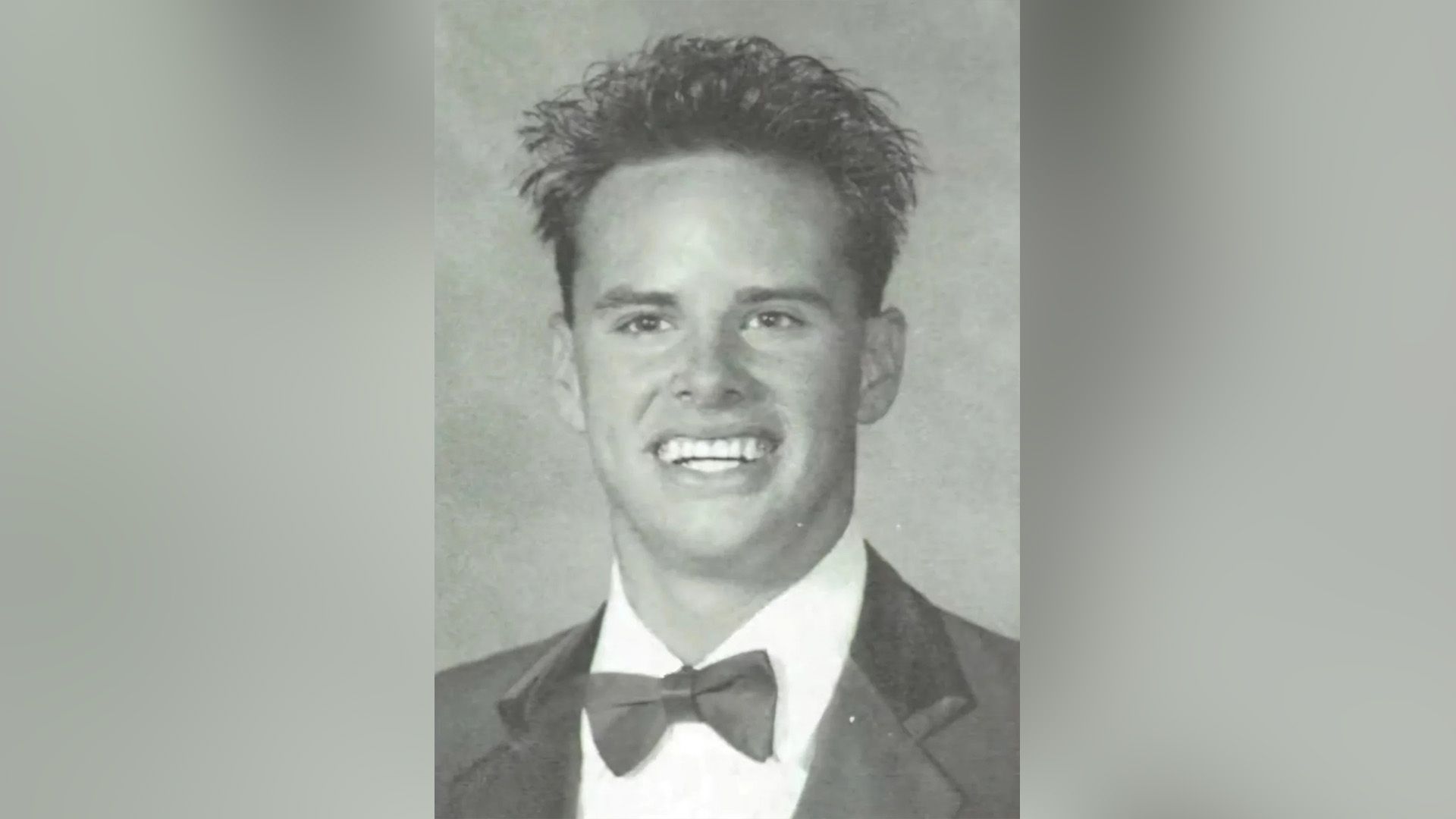 Giovane Walton Goggins, vestito con un papillon, sorride ampiamente in una foto dall'album scolastico