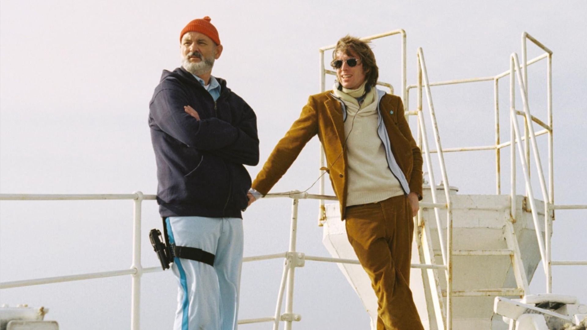L'attore Bill Murray con un cappello rosso e il regista Wes Anderson con una giacca marrone si tengono alla ringhiera della nave contro il cielo