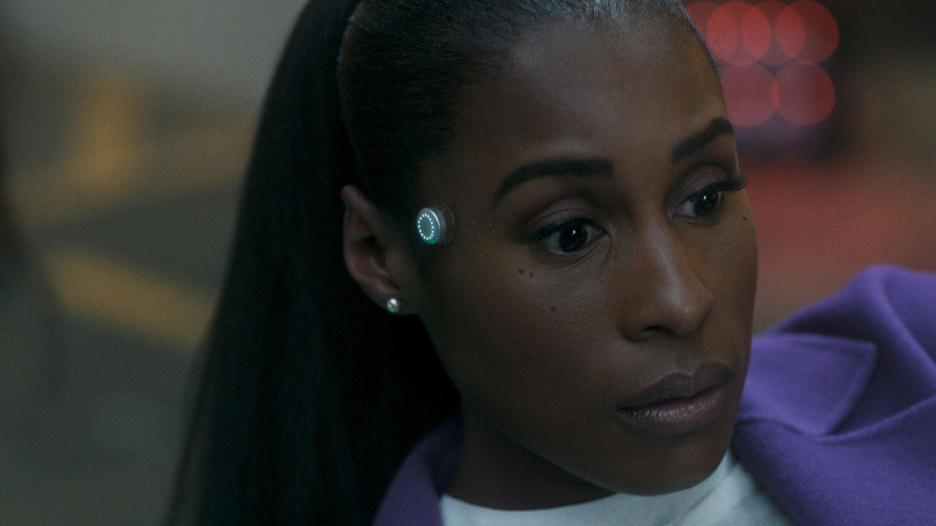 Issa Rae guarda pensierosa di lato, con un indicatore metallico rotondo che brilla sulla sua tempia