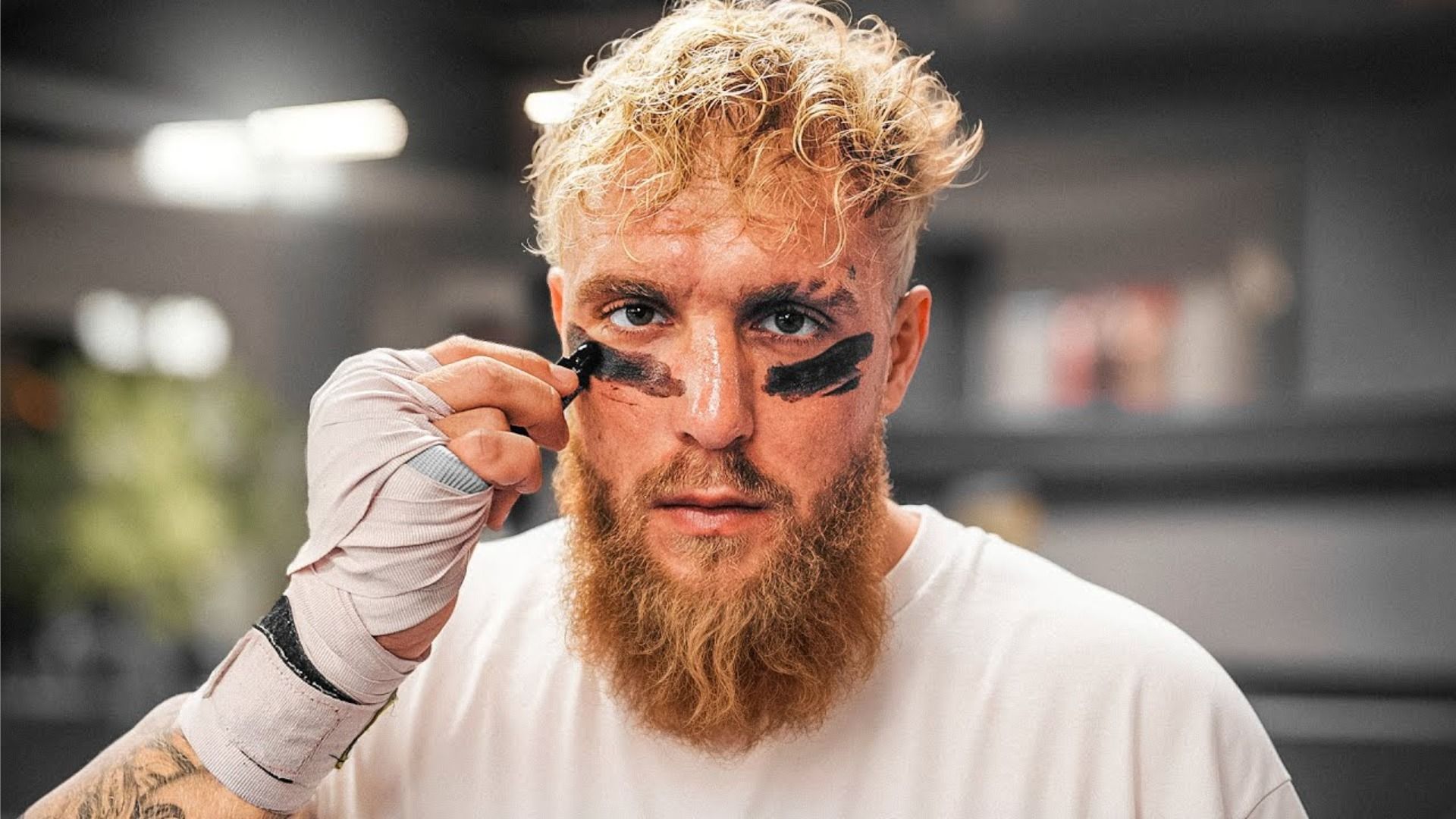 Il blogger Jake Paul in maglietta bianca e in tenuta da giocatore di football