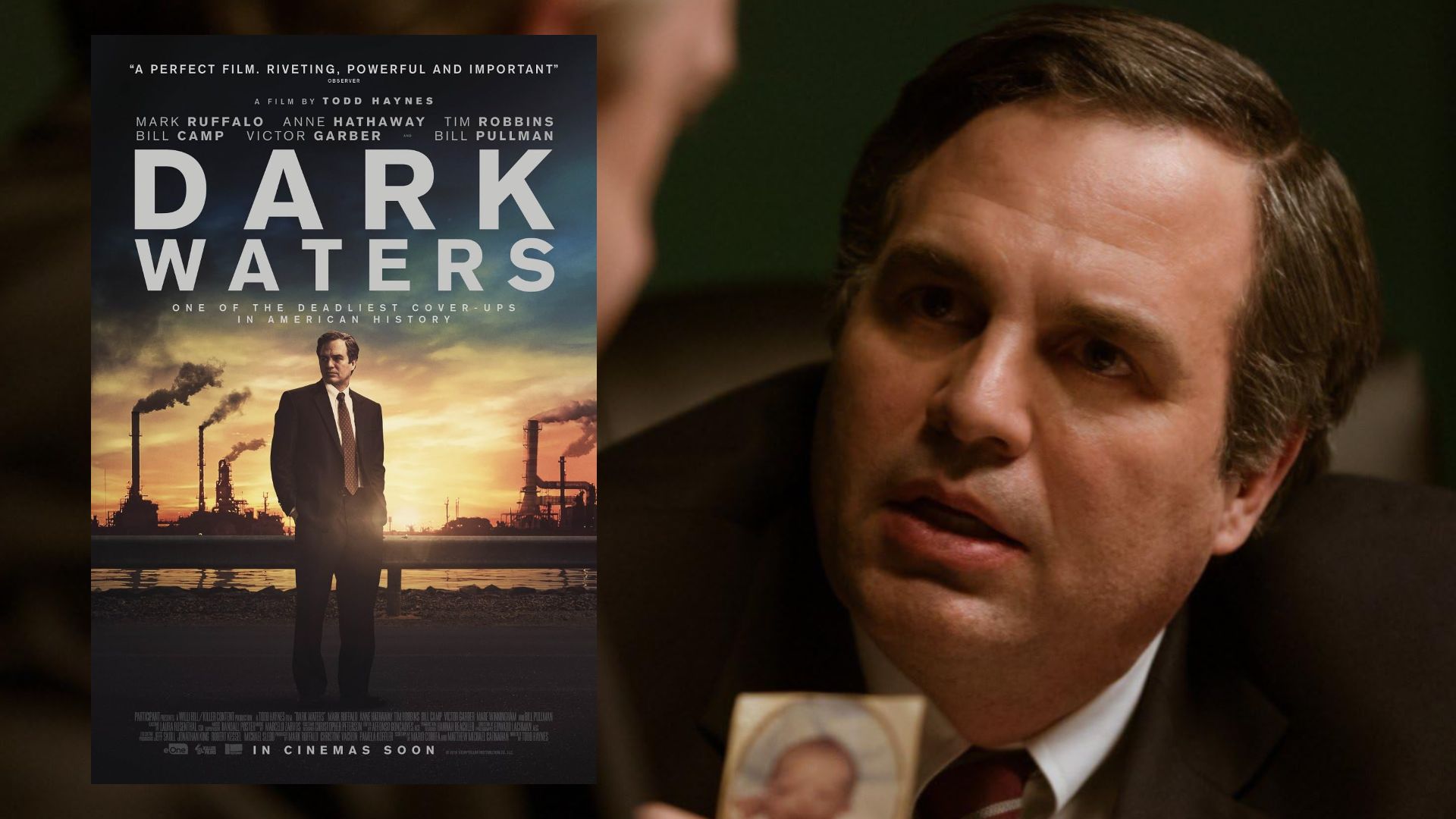 L'attore Mark Ruffalo in giacca nera mostra una fotografia e guarda di lato