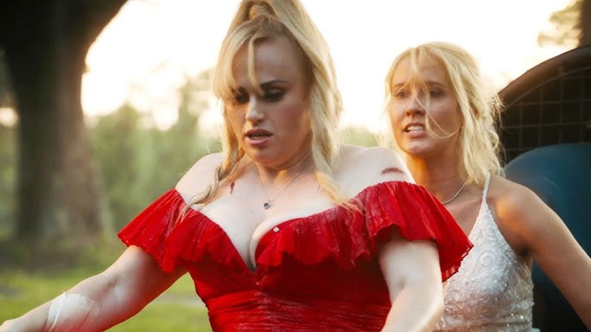 Rebel Wilson in abito rosso e Anna Camp in bianco in bicicletta