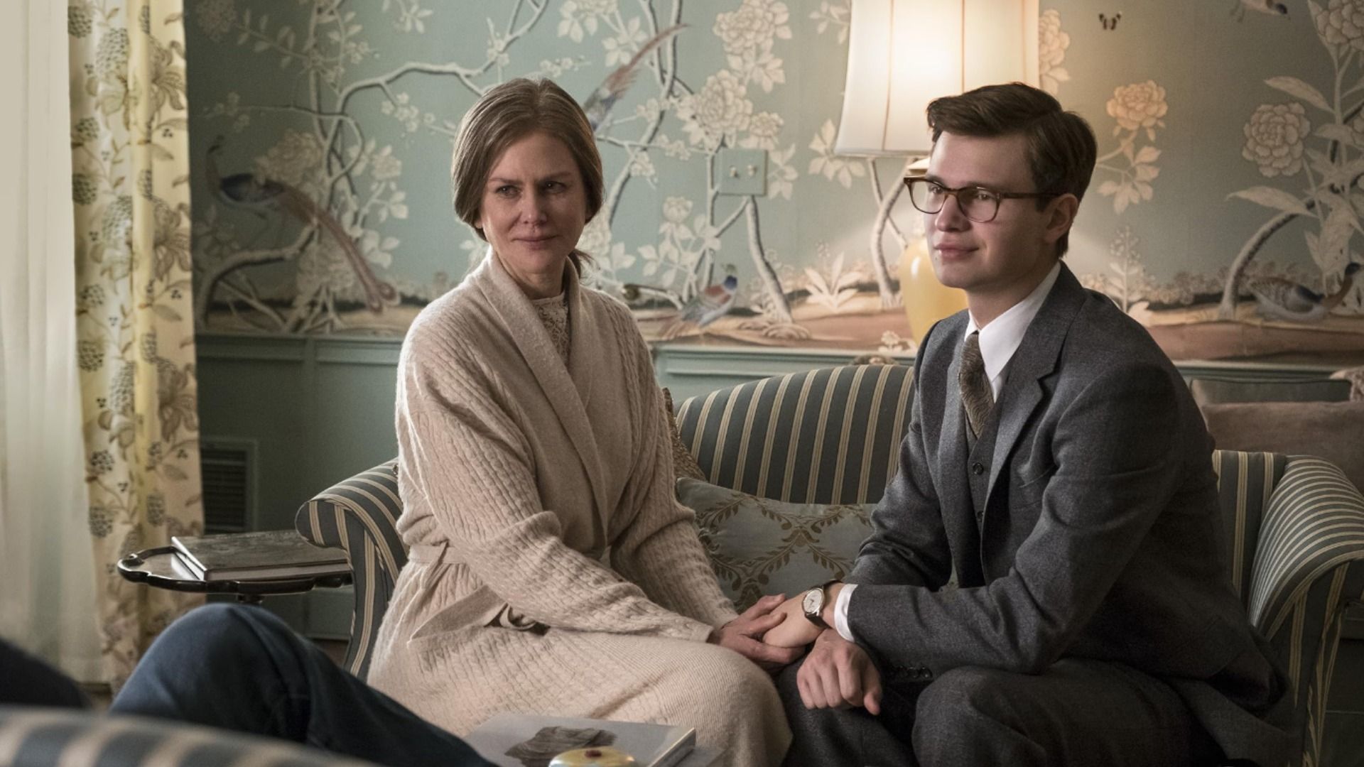 L'attrice Nicole Kidman in abito bianco e l'attore Ansel Elgort in giacca grigia seduti su un divano