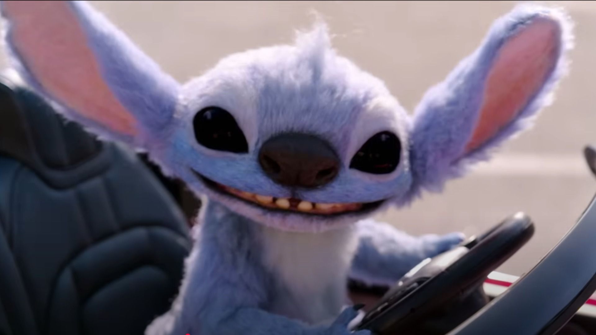 L'alieno blu Stitch seduto al volante di una piccola auto e sorride