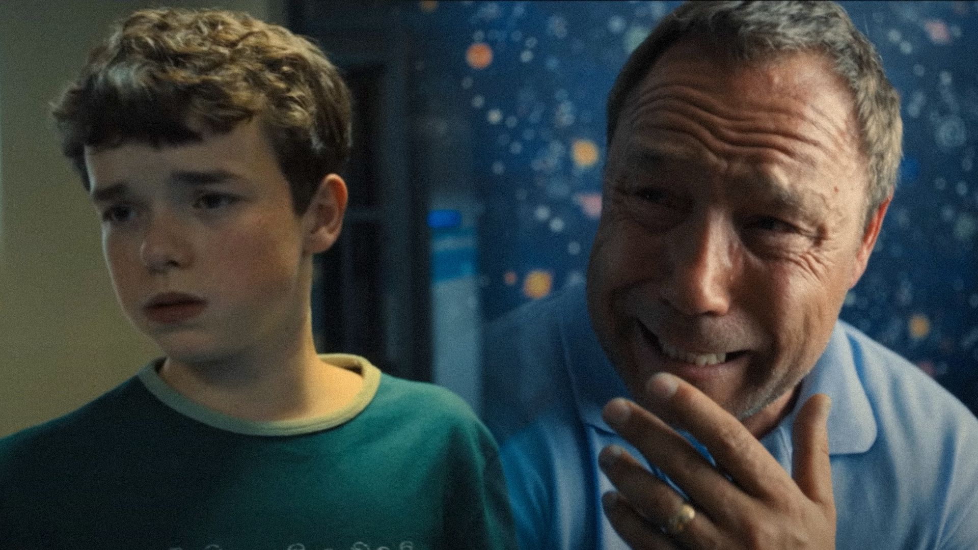 Owen Cooper in green clothing looks to the side and actor Stephen Graham cries in a blue room