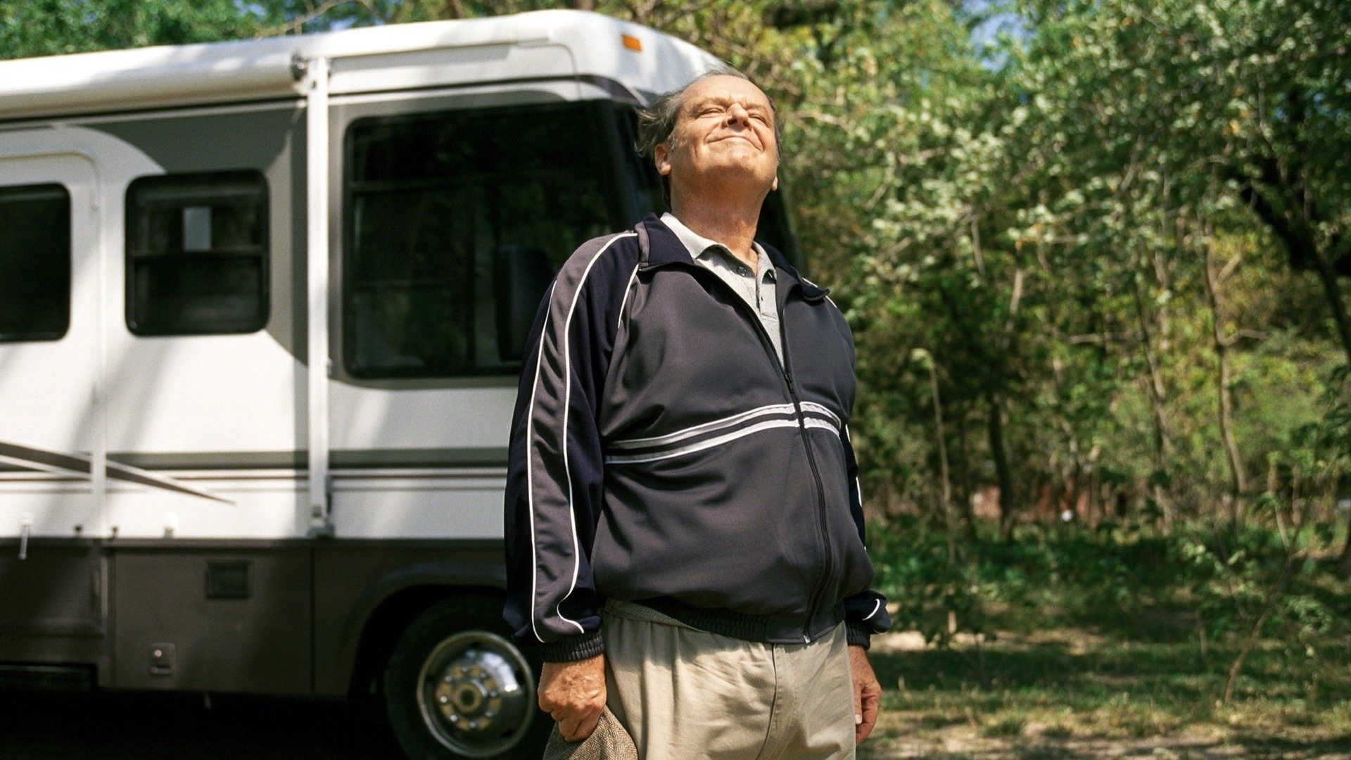 Jack Nicholson in tuta davanti a un camper che si gode una giornata di sole circondato dagli alberi