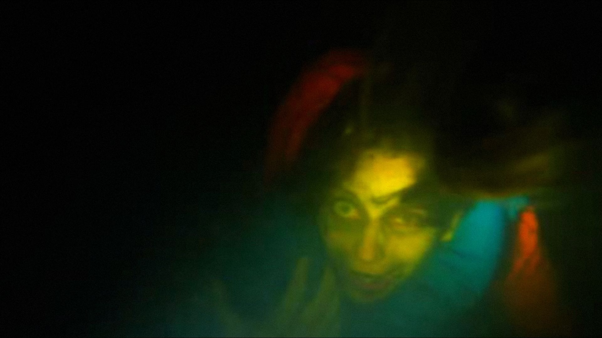 Donna in abiti arancioni guarda la telecamera sott'acqua