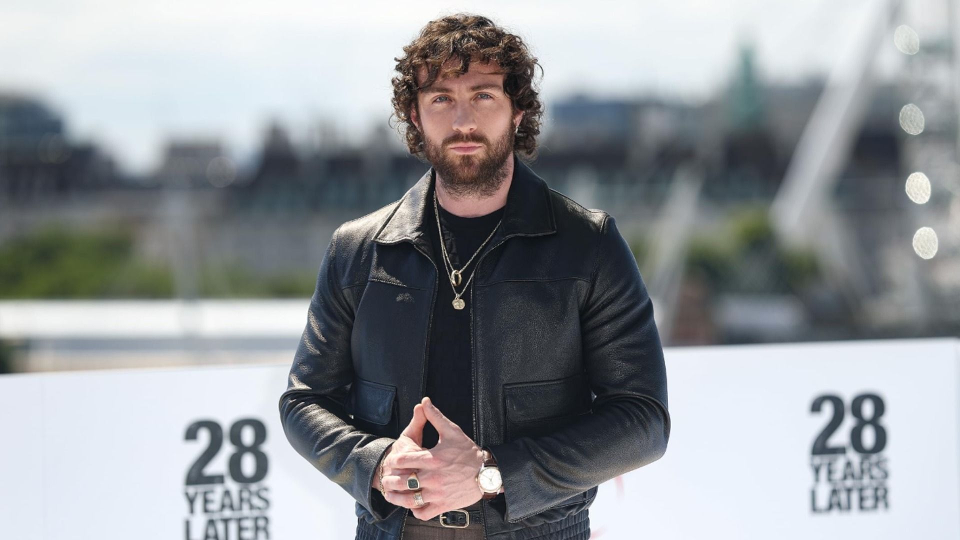 L'attore Aaron Taylor-Johnson in giacca di pelle nera sullo sfondo sfocato della città